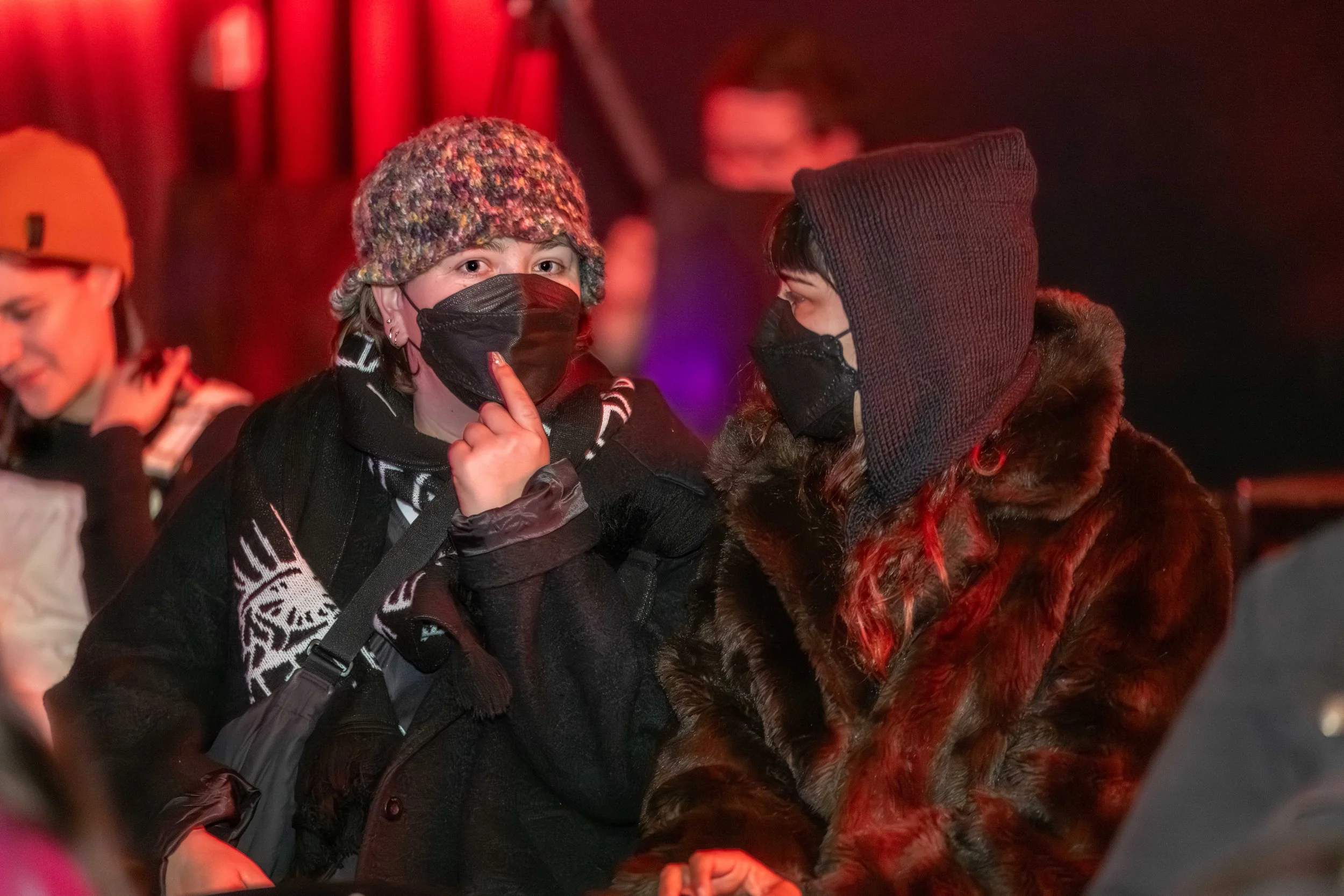 Two humans in masks talk to each other.