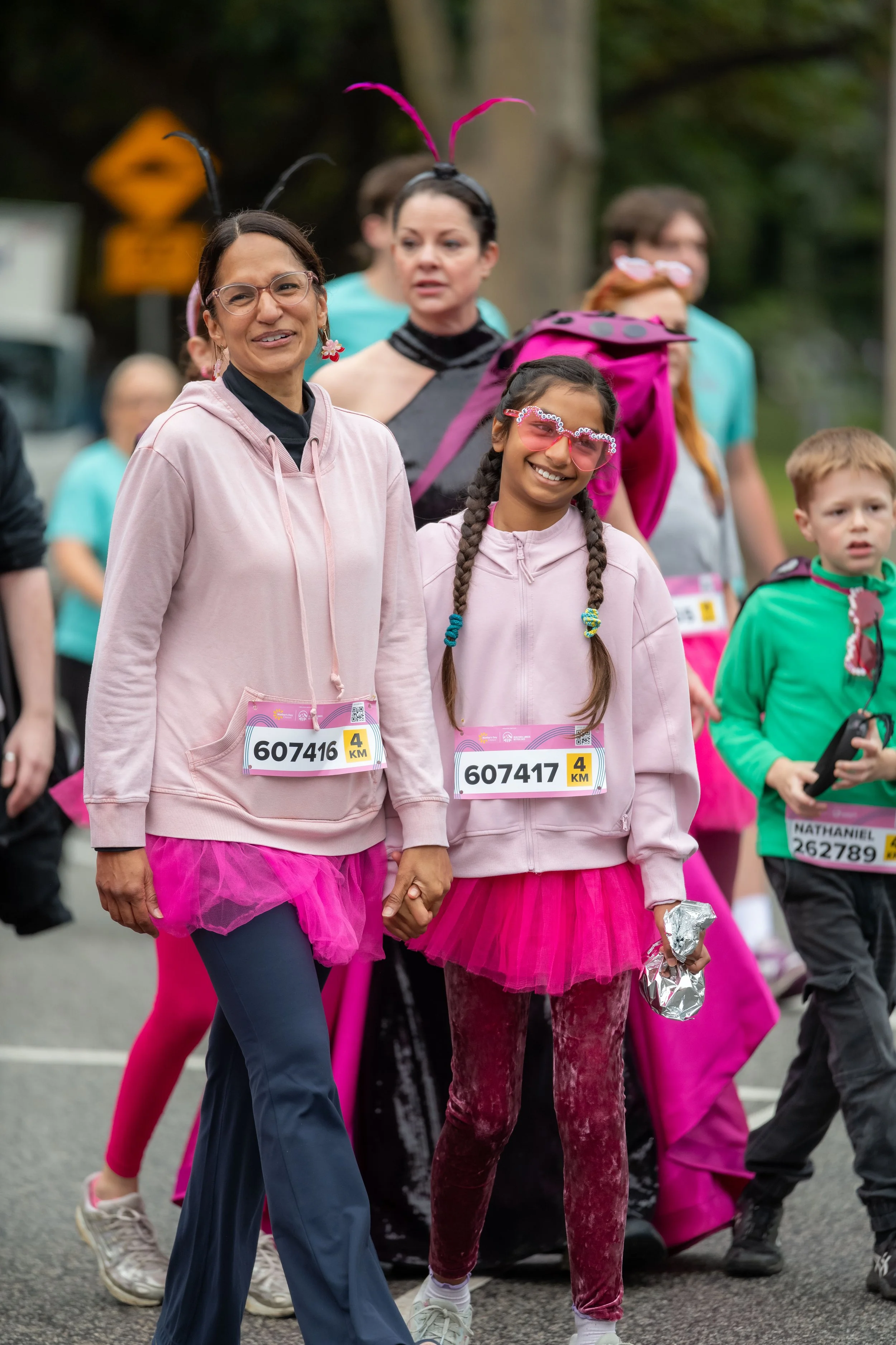 Two racegoers wearing pink smile at the camera.