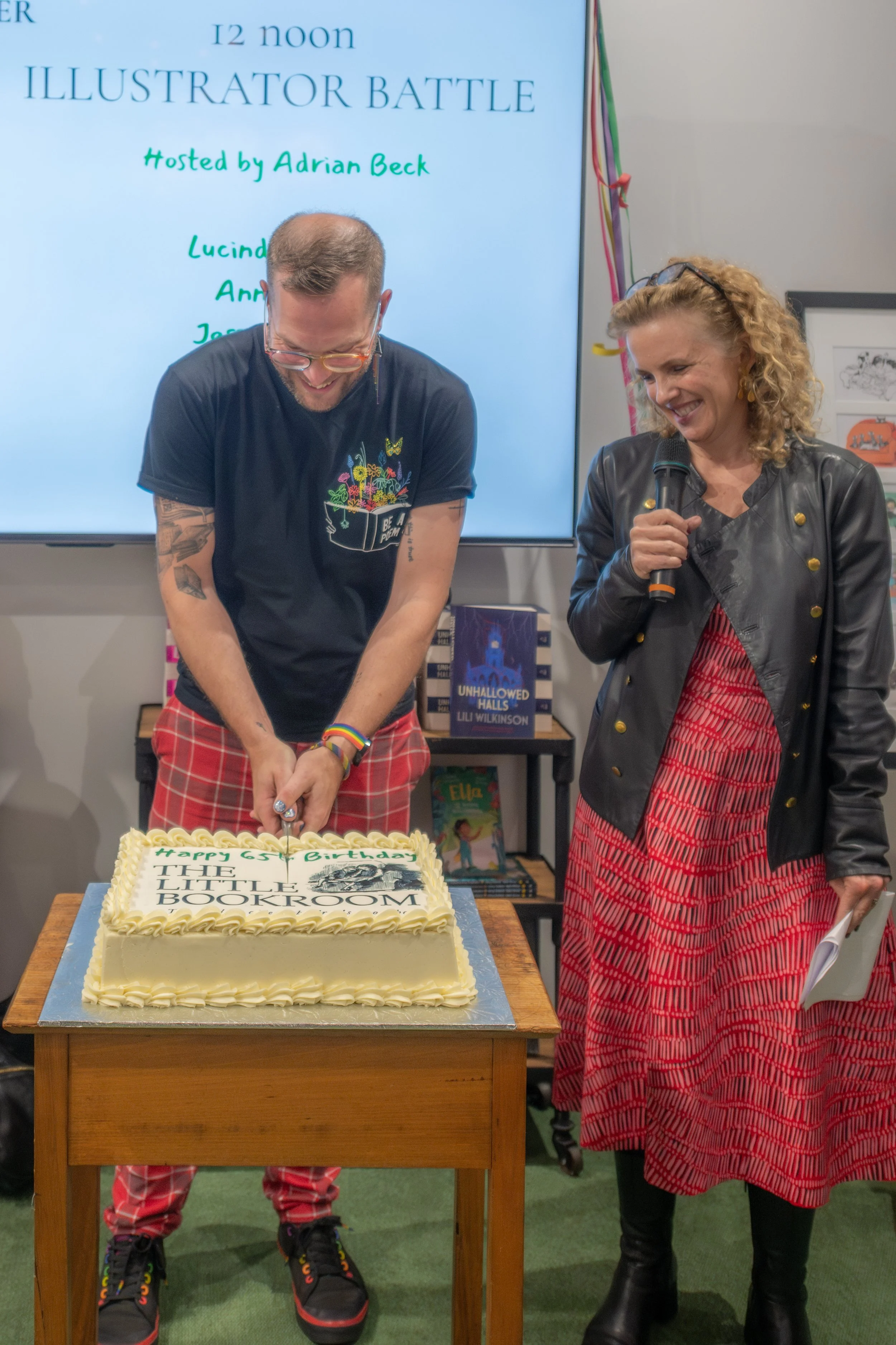 Michael Earp cuts a large cream-coloured cake as Sally Rippin looks on.