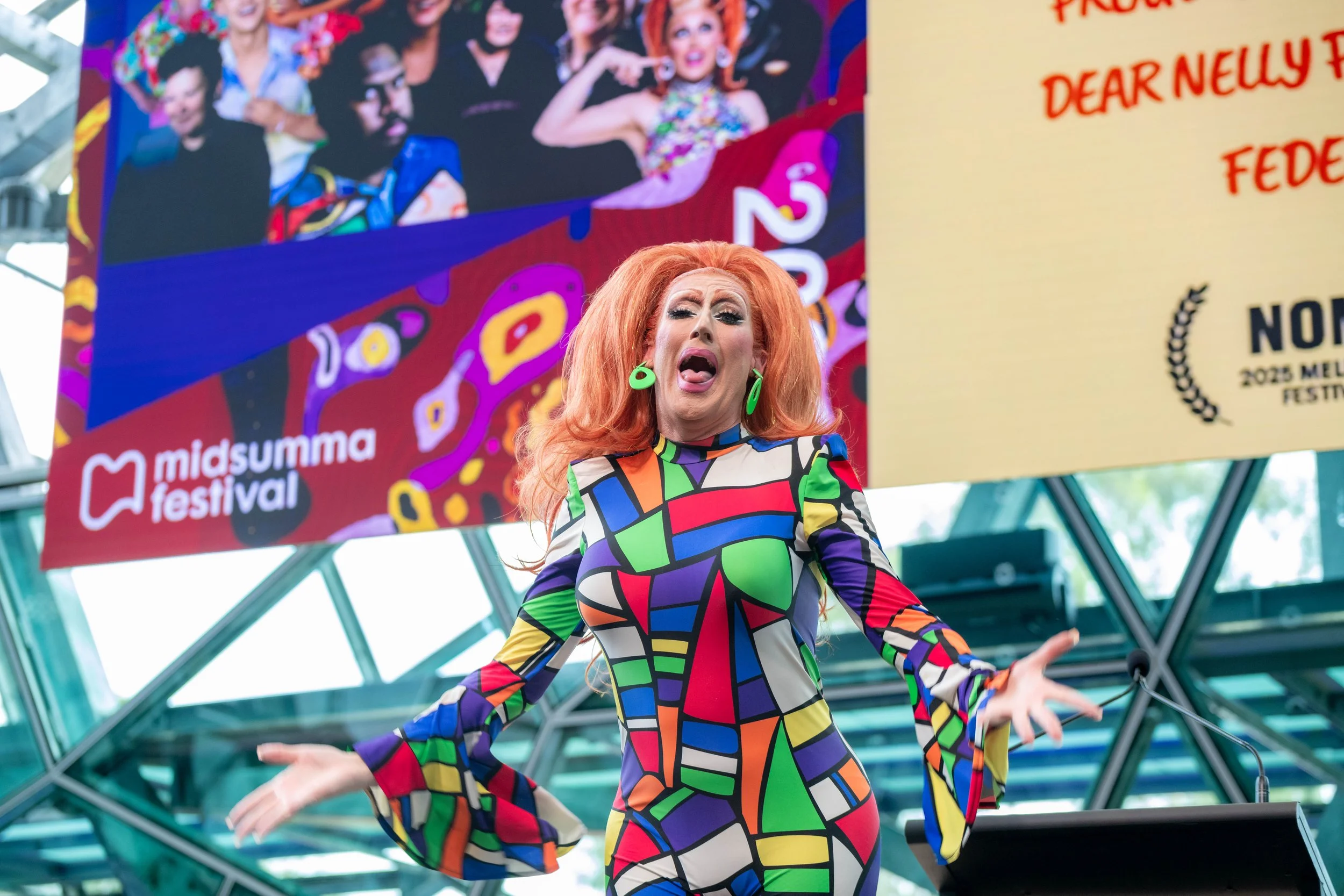 Poly Filla dances and lip syncs, their hands are splayed outwards.