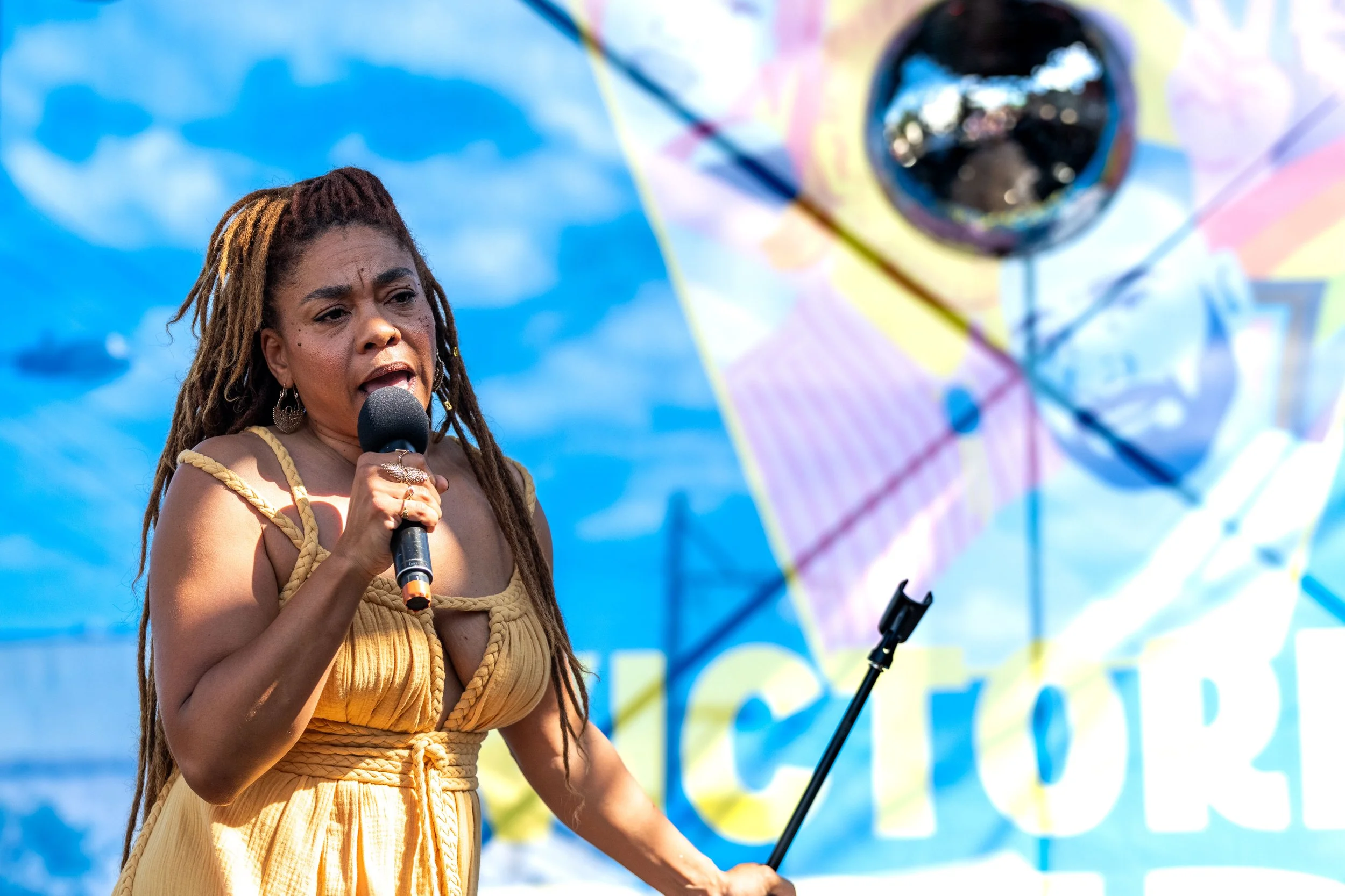 Cle Morgan sings into a microphone and holds the stand off to the side.