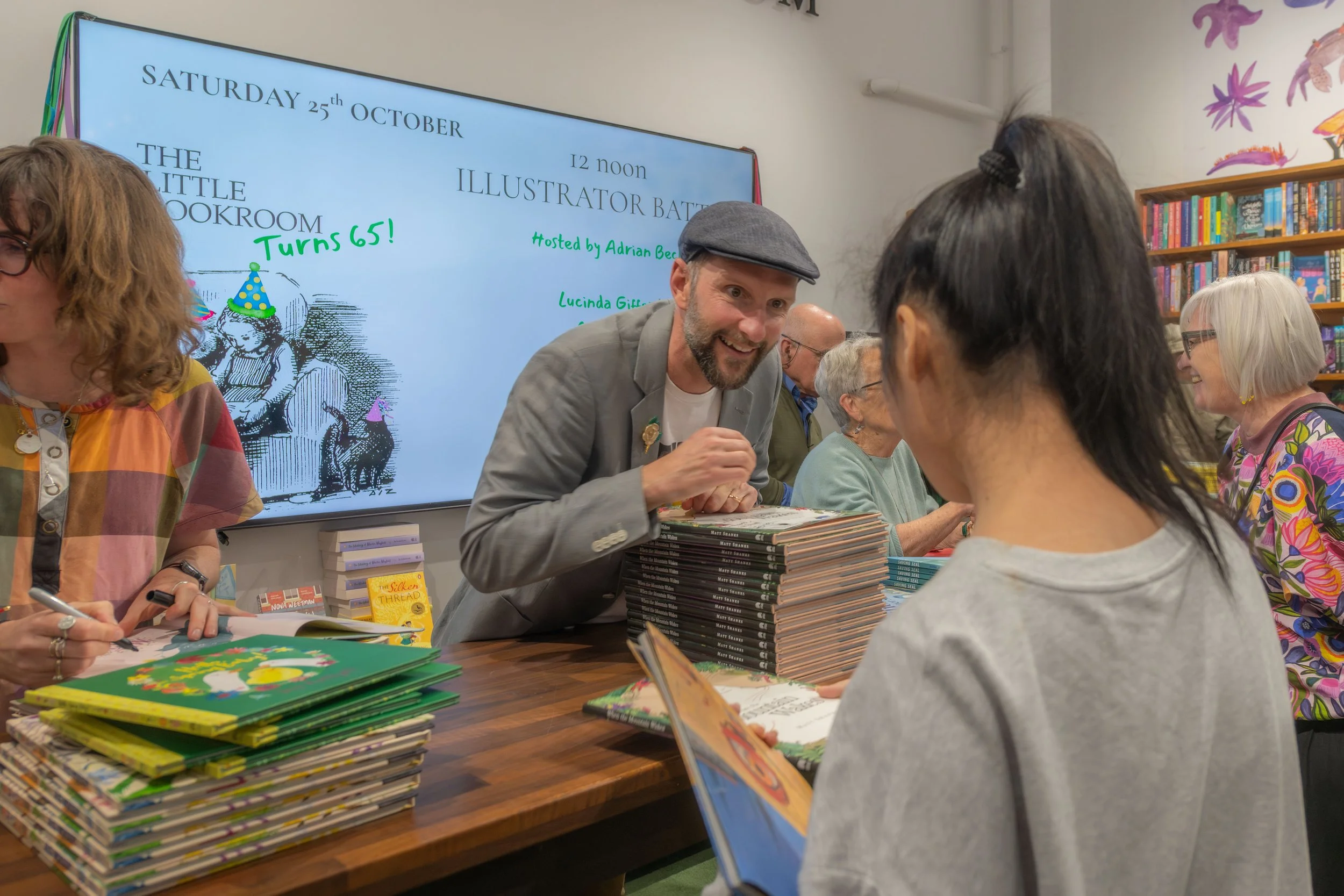 Illustrators sign large stacks of books.