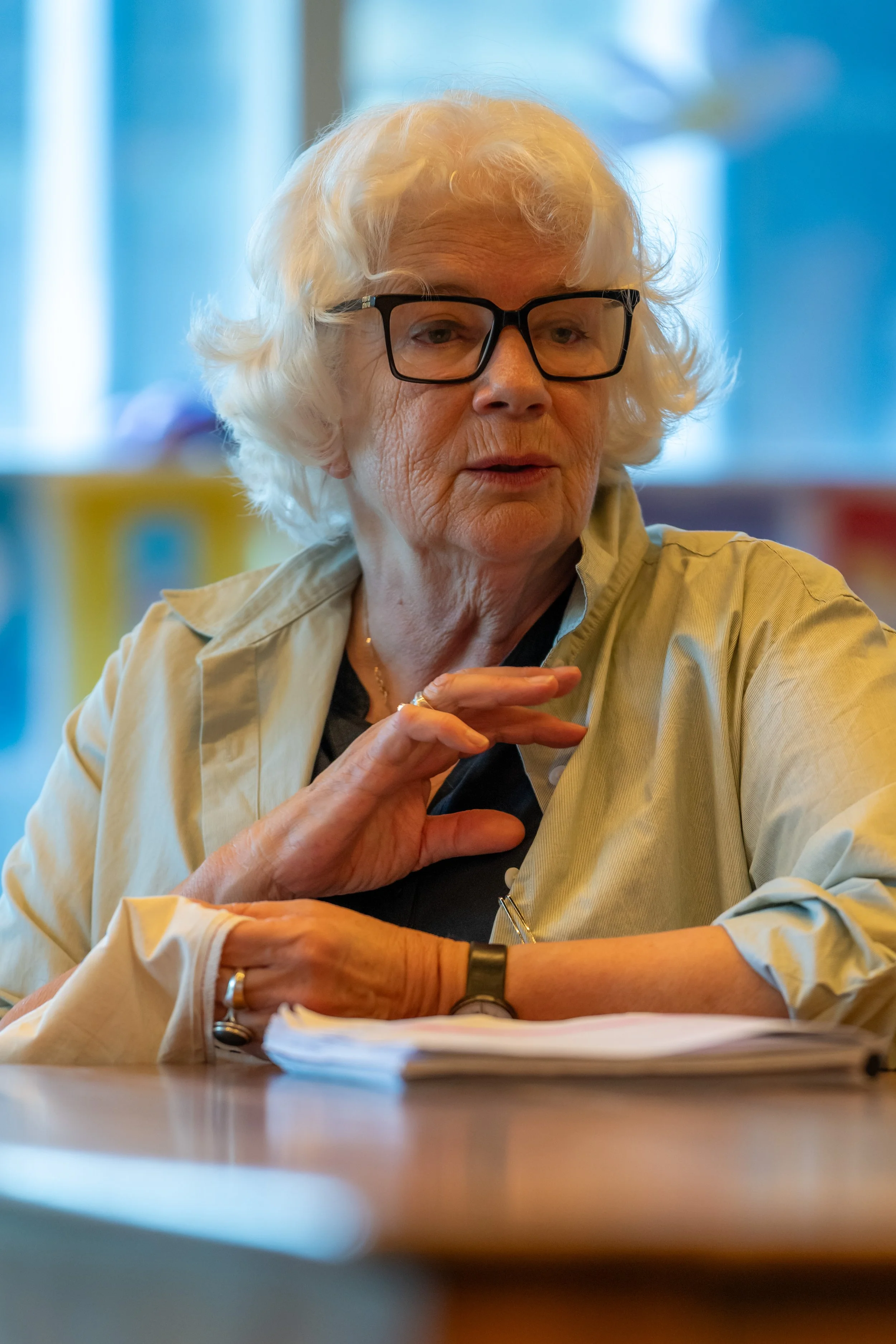 A human with white hair sits at a table. There are pages of notes in front of them.