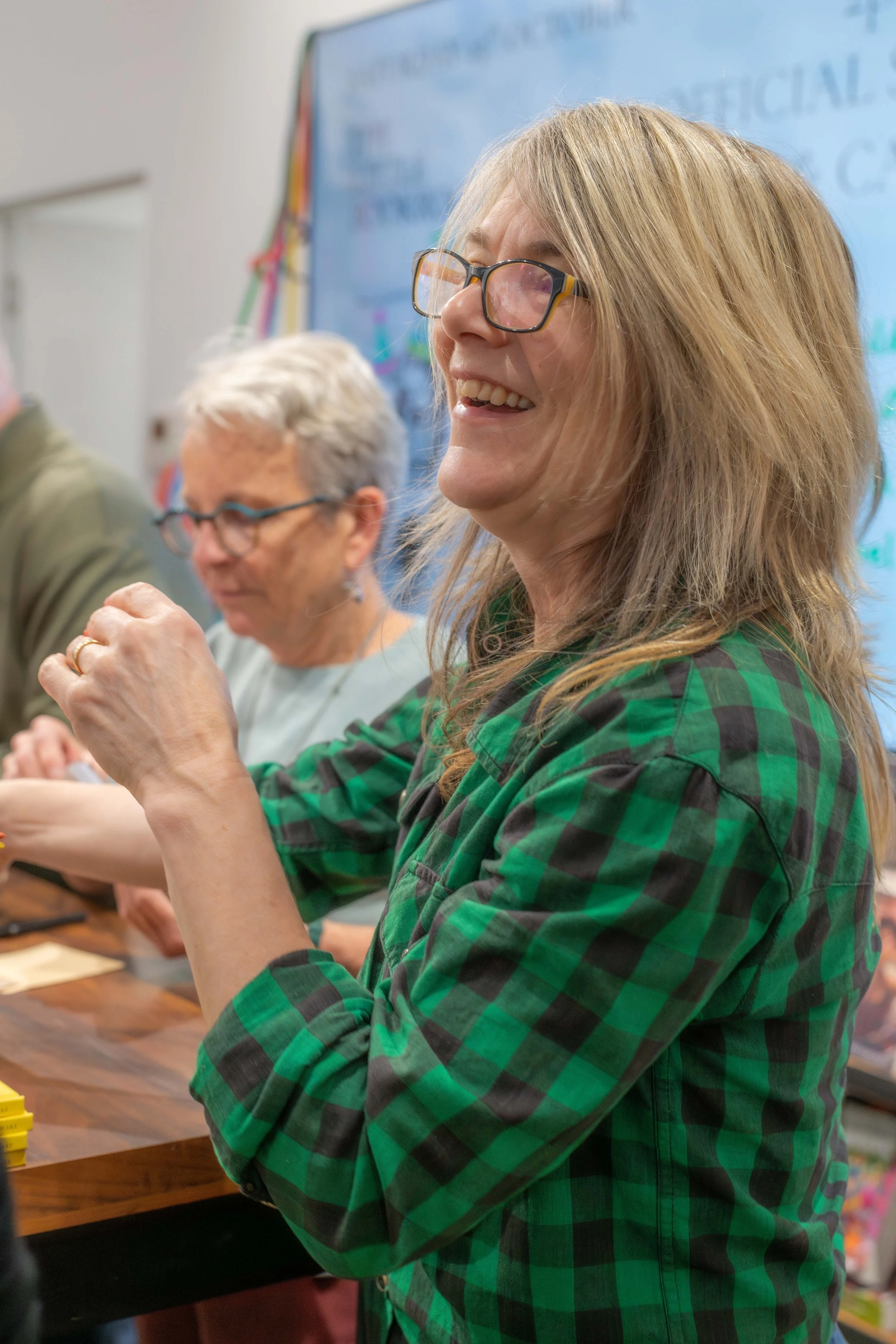 An illustrator smiles as they sign books.
