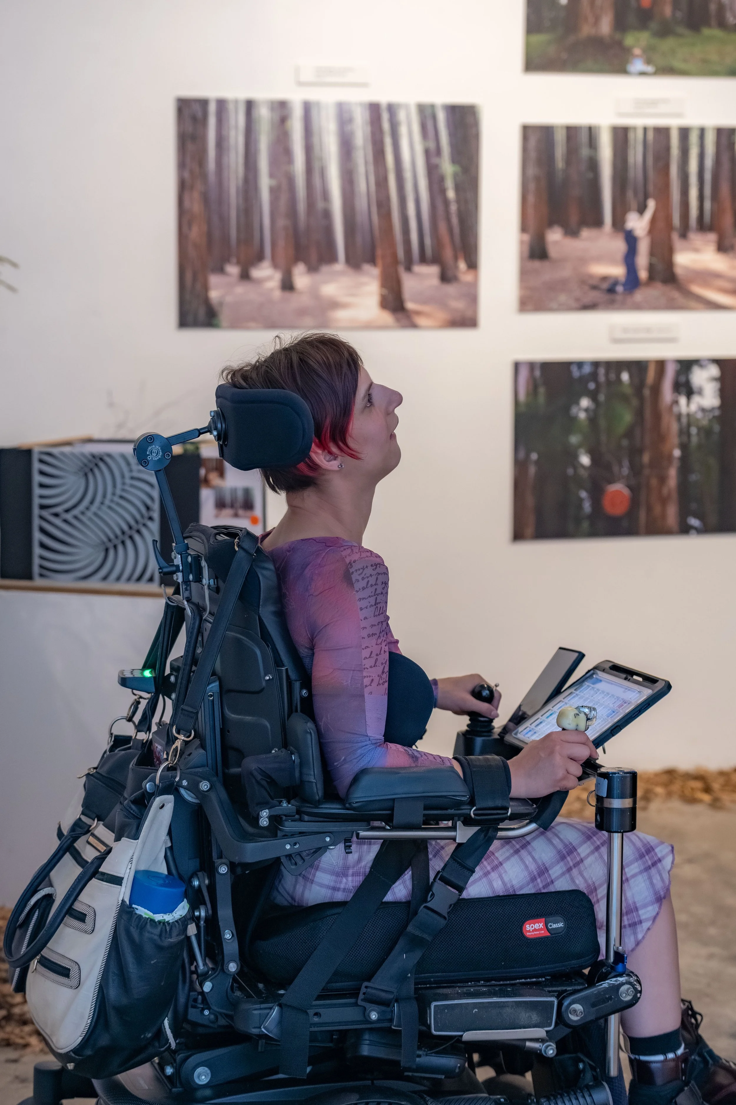 Nicole Tsourlenes with their photography work in the background.