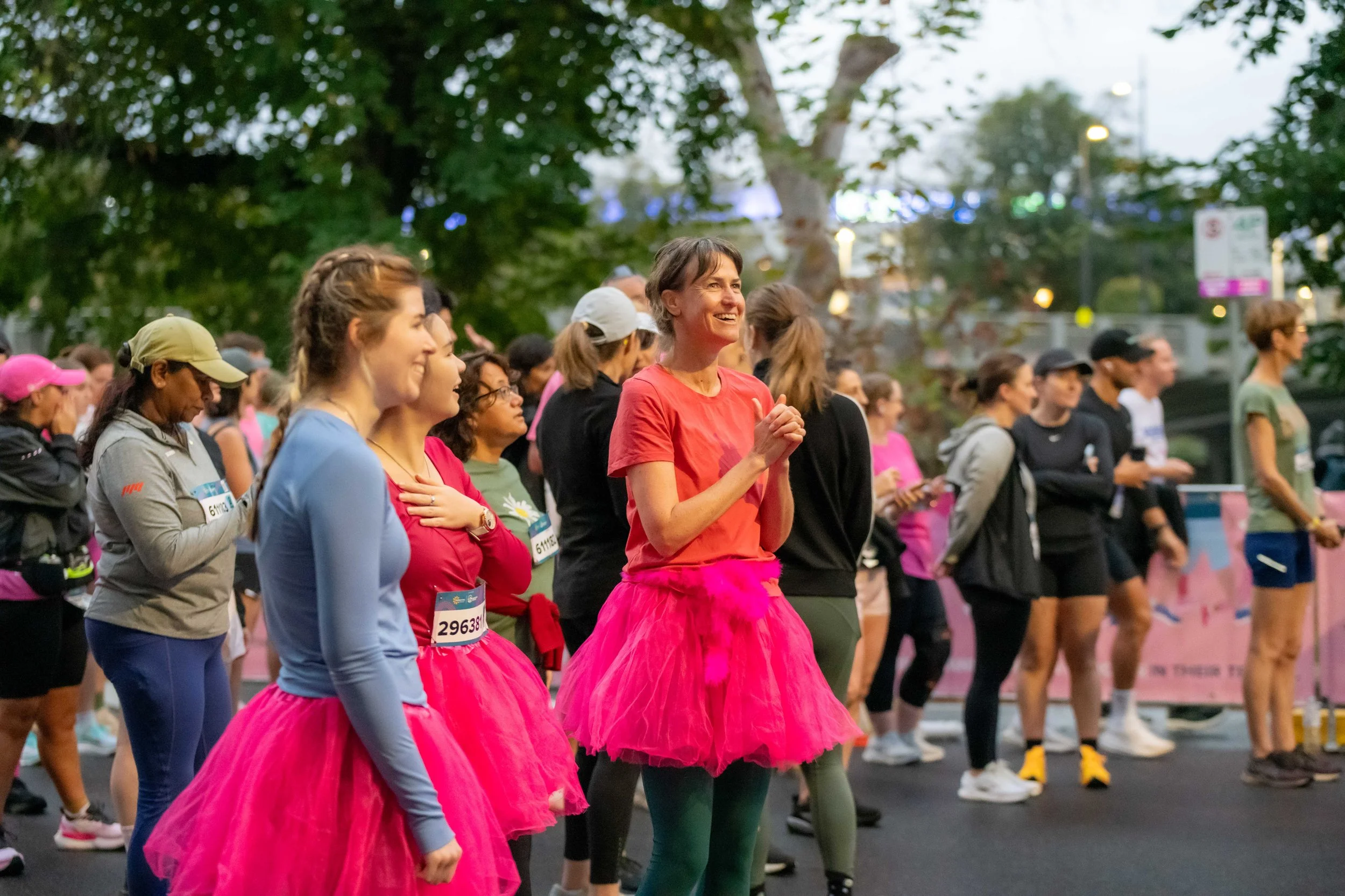 Racegoers wearing pink tutus wait at the start line.