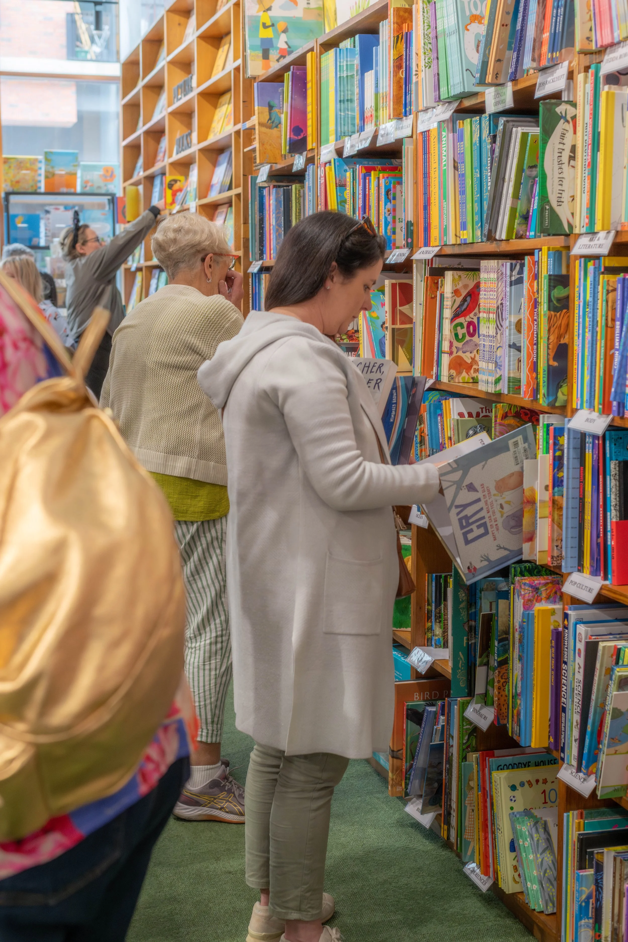 A human looks through shelves of books.