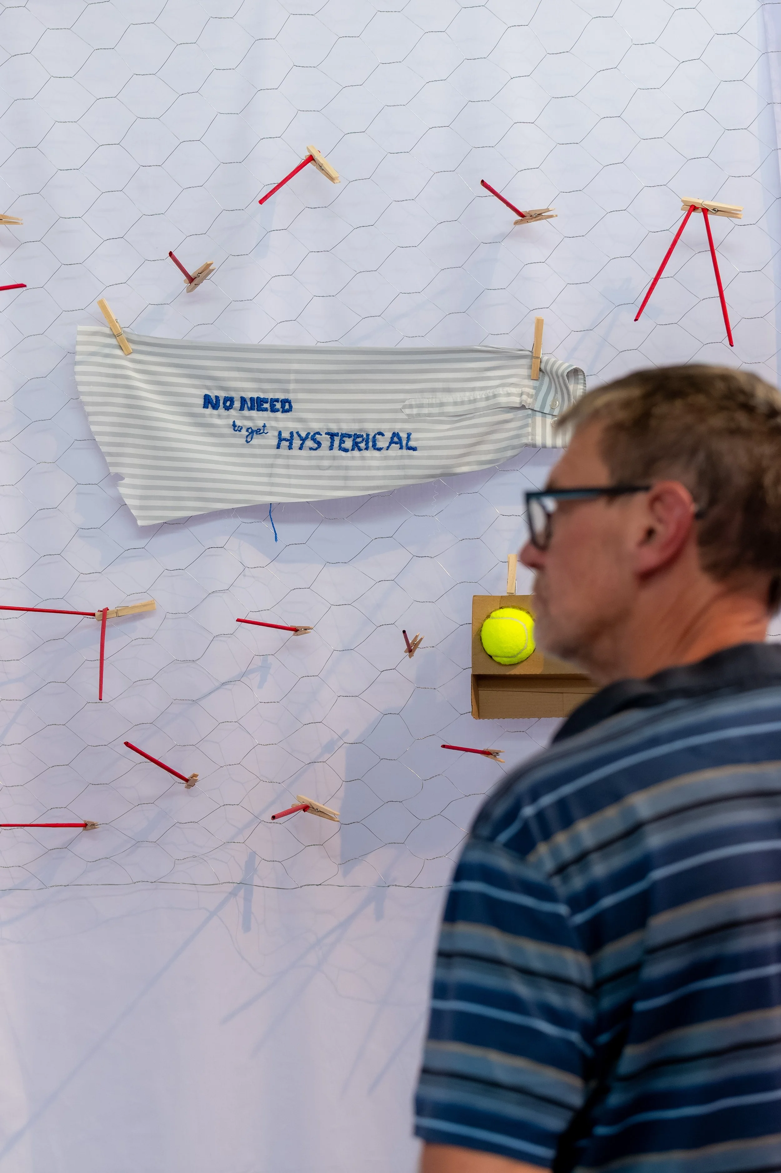 A human looks at an artwork that states "No need to get hysterical".