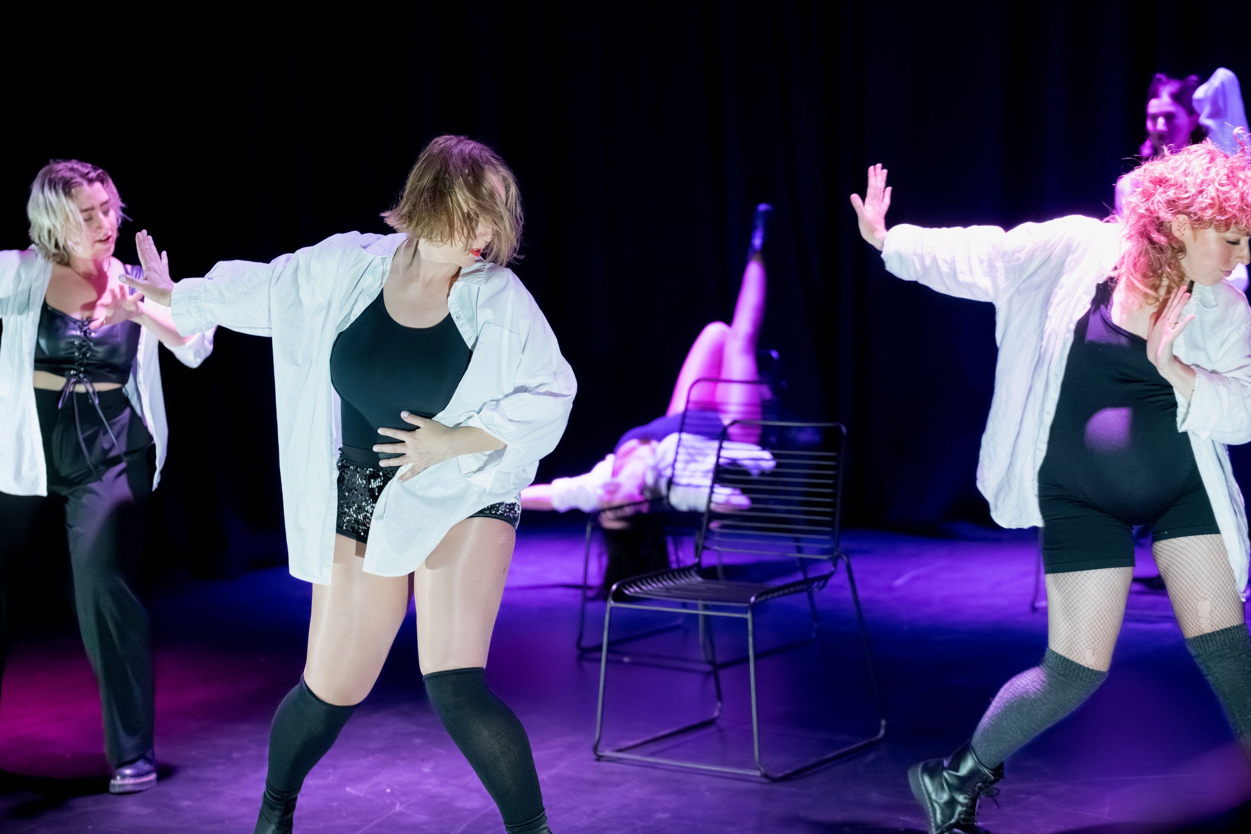 Dancers in white and black on stage. One dancer is heavily pregnant.