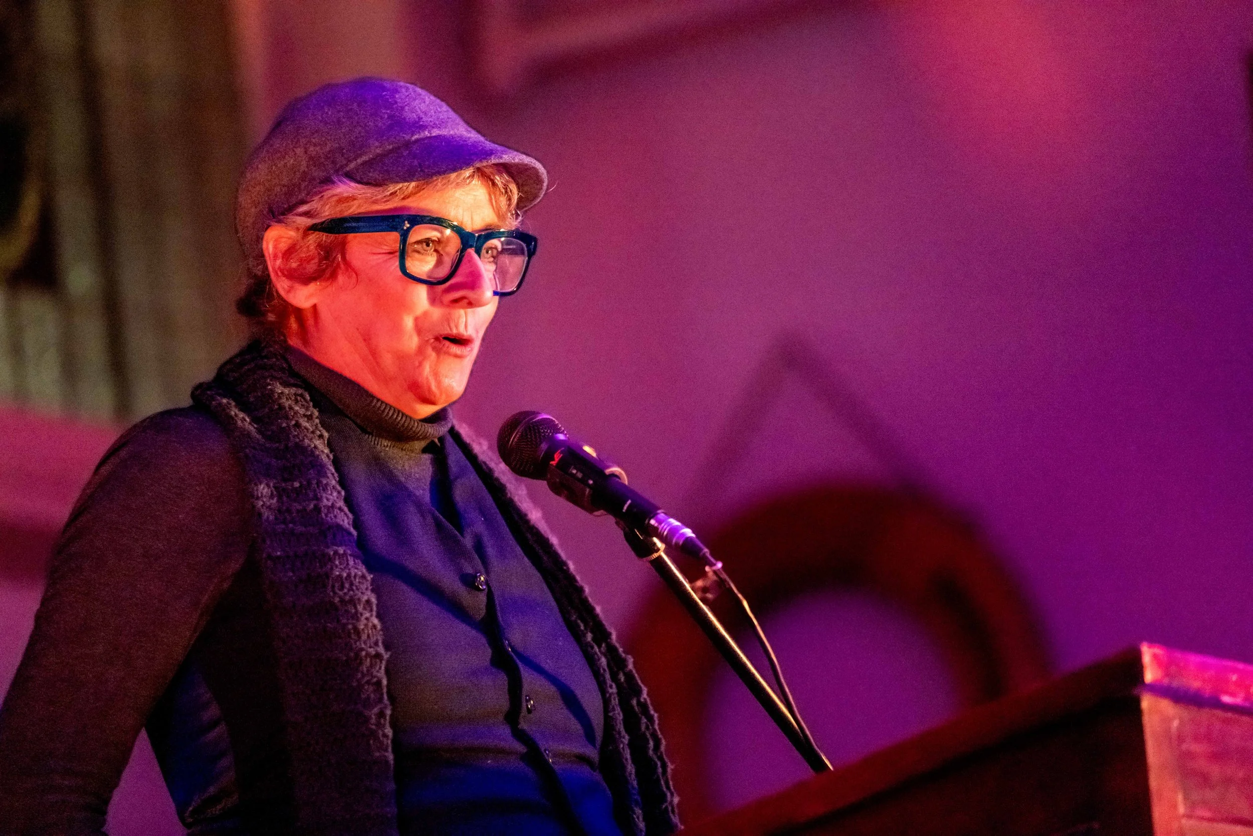 A human speaks into the microphone whilst looking at an unseen audience.