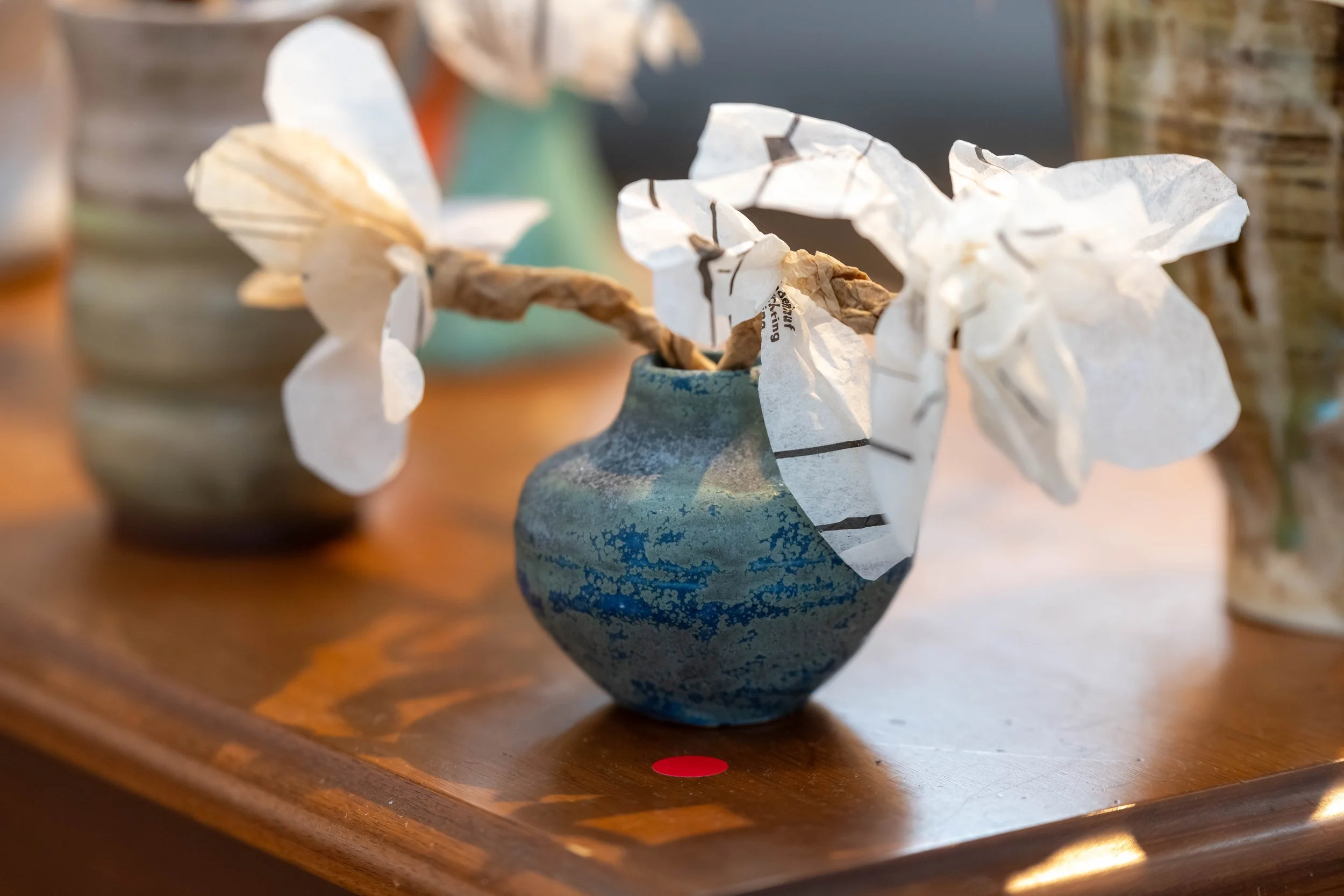 A paper and ceramic sculpture with a red (sold) dot next to it.