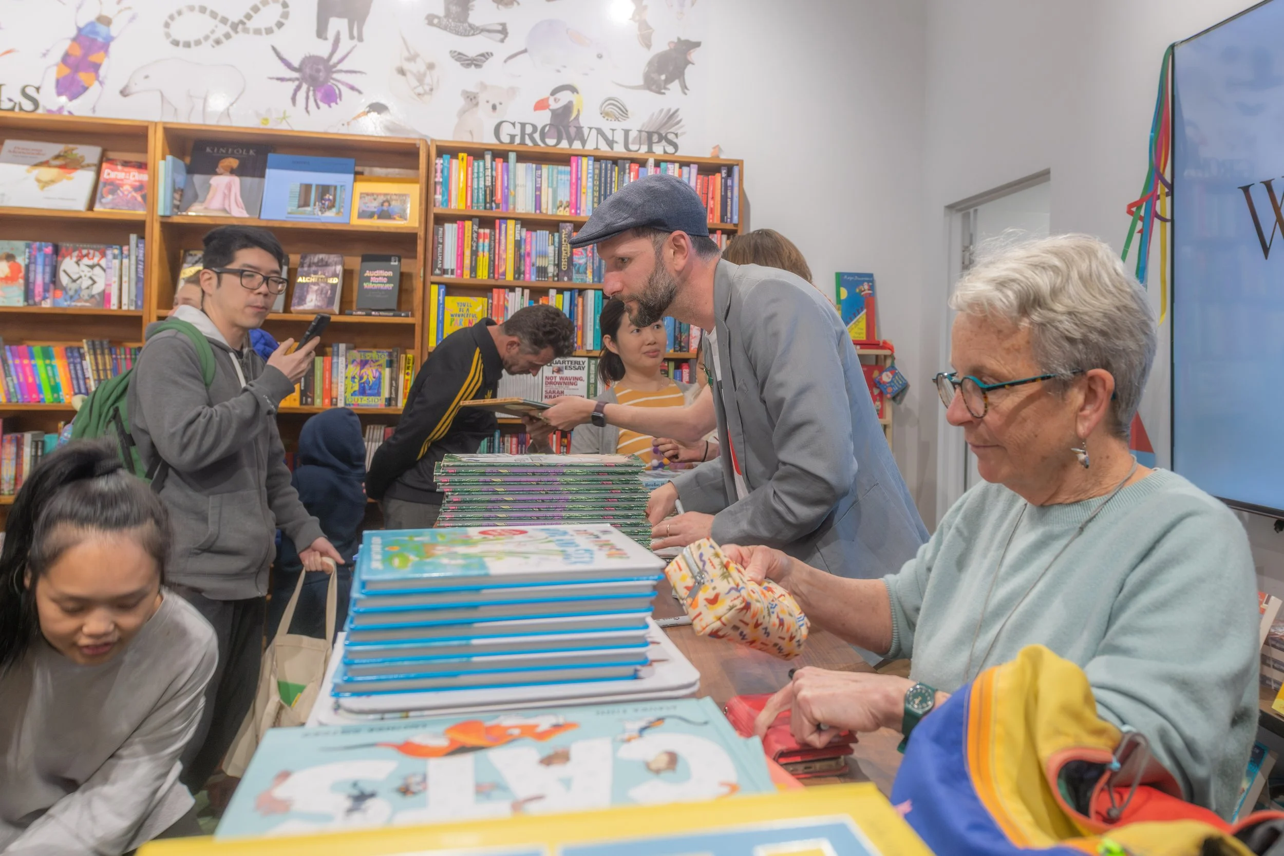 Illustrators sign large stacks of books.