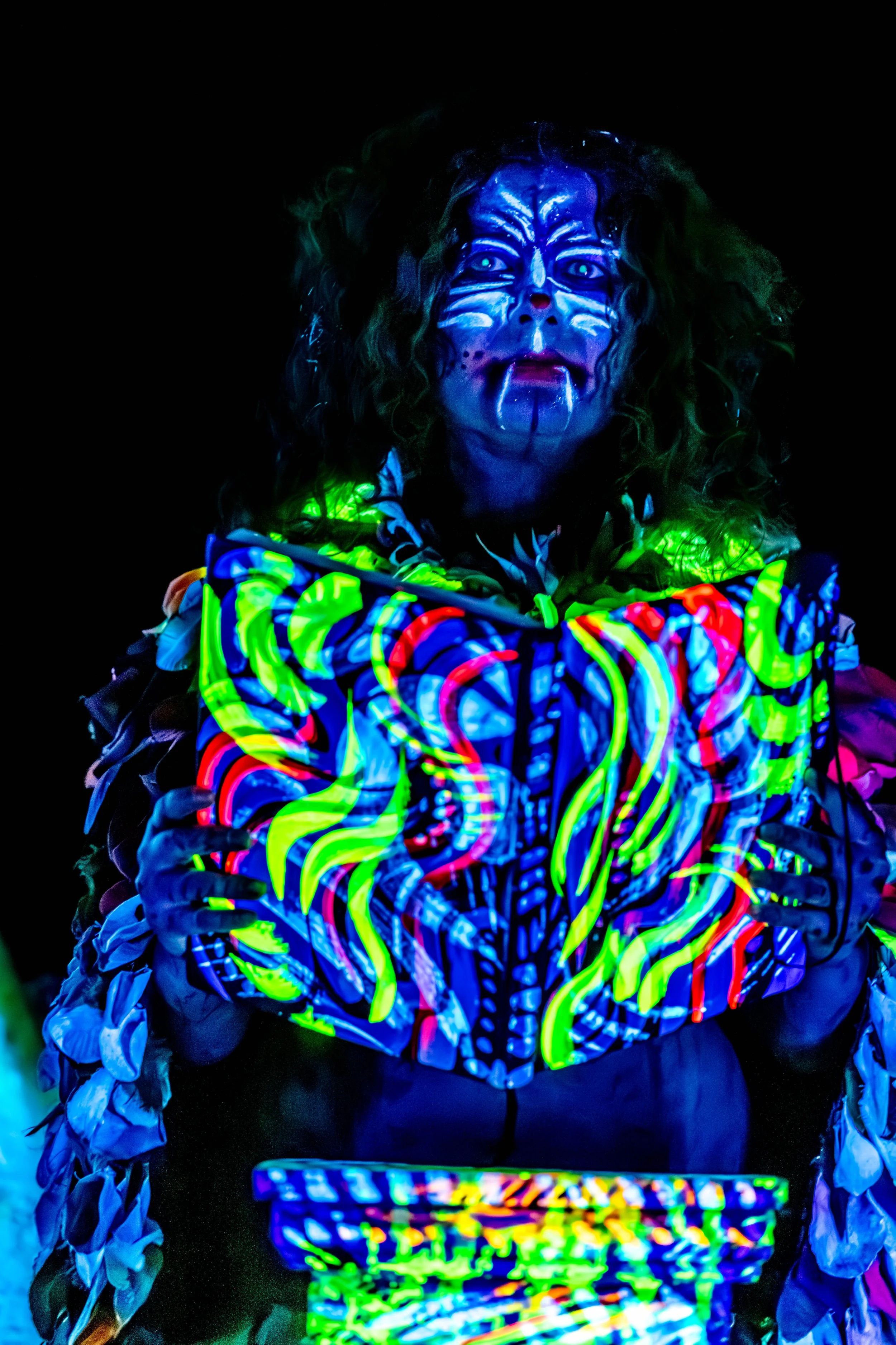 Jessie Ngaio has glow in the dark face paint on and holds up an ornate book also covered in paint markings.
