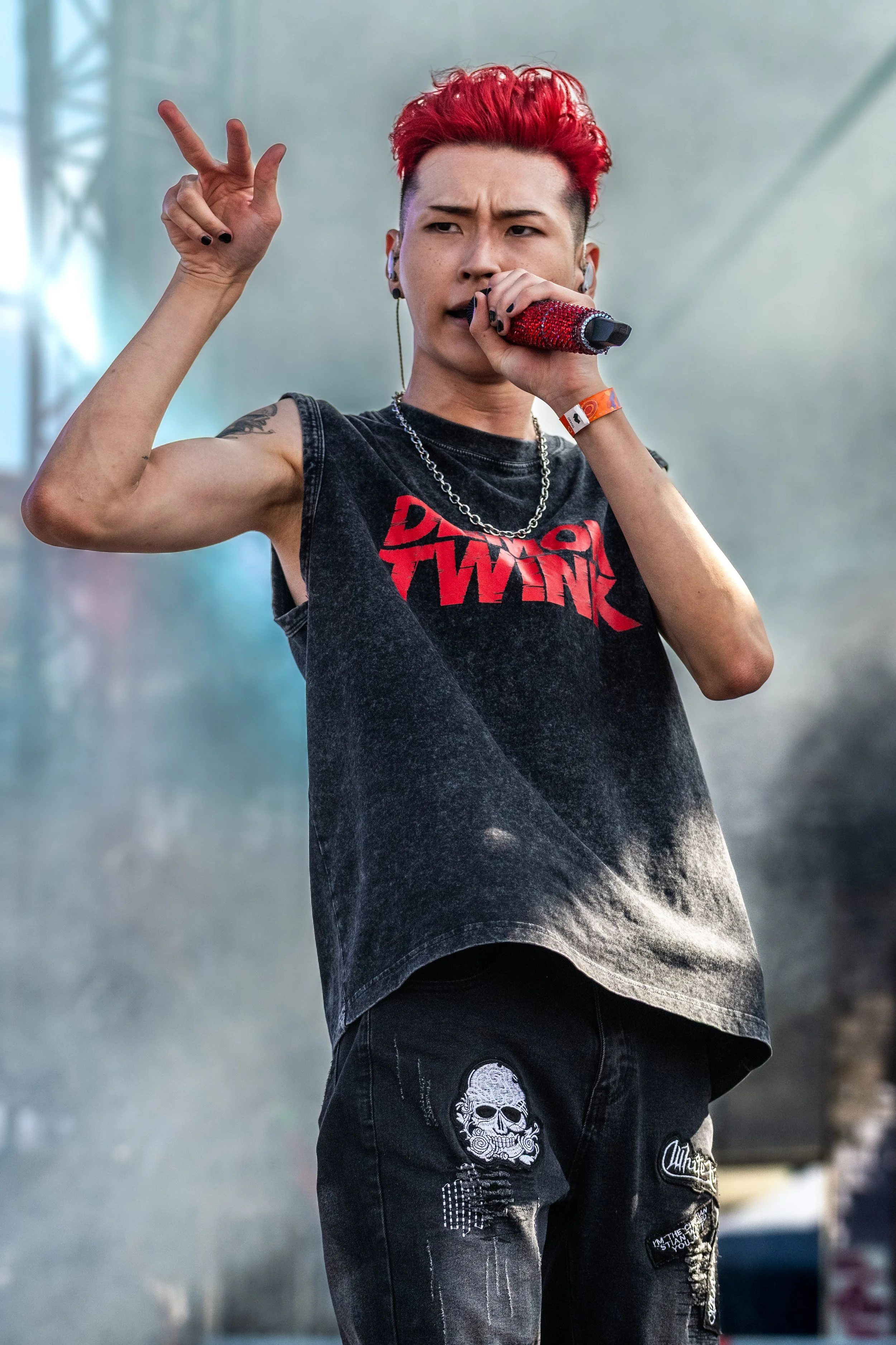 Kevin Silvester sings into a microphone and holds three fingers up.