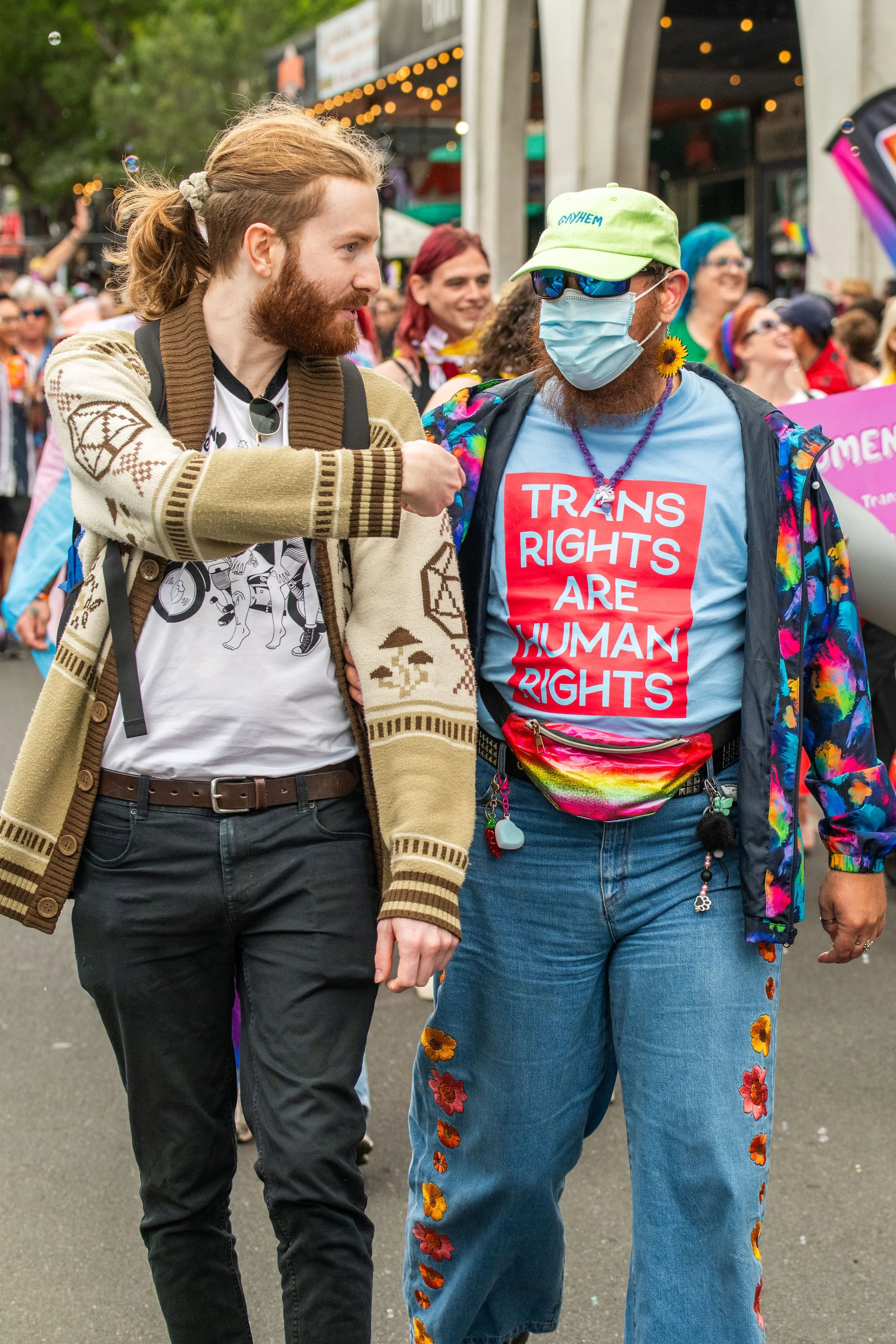 Two humans talking as they march. One human wears a surgical face mask.
