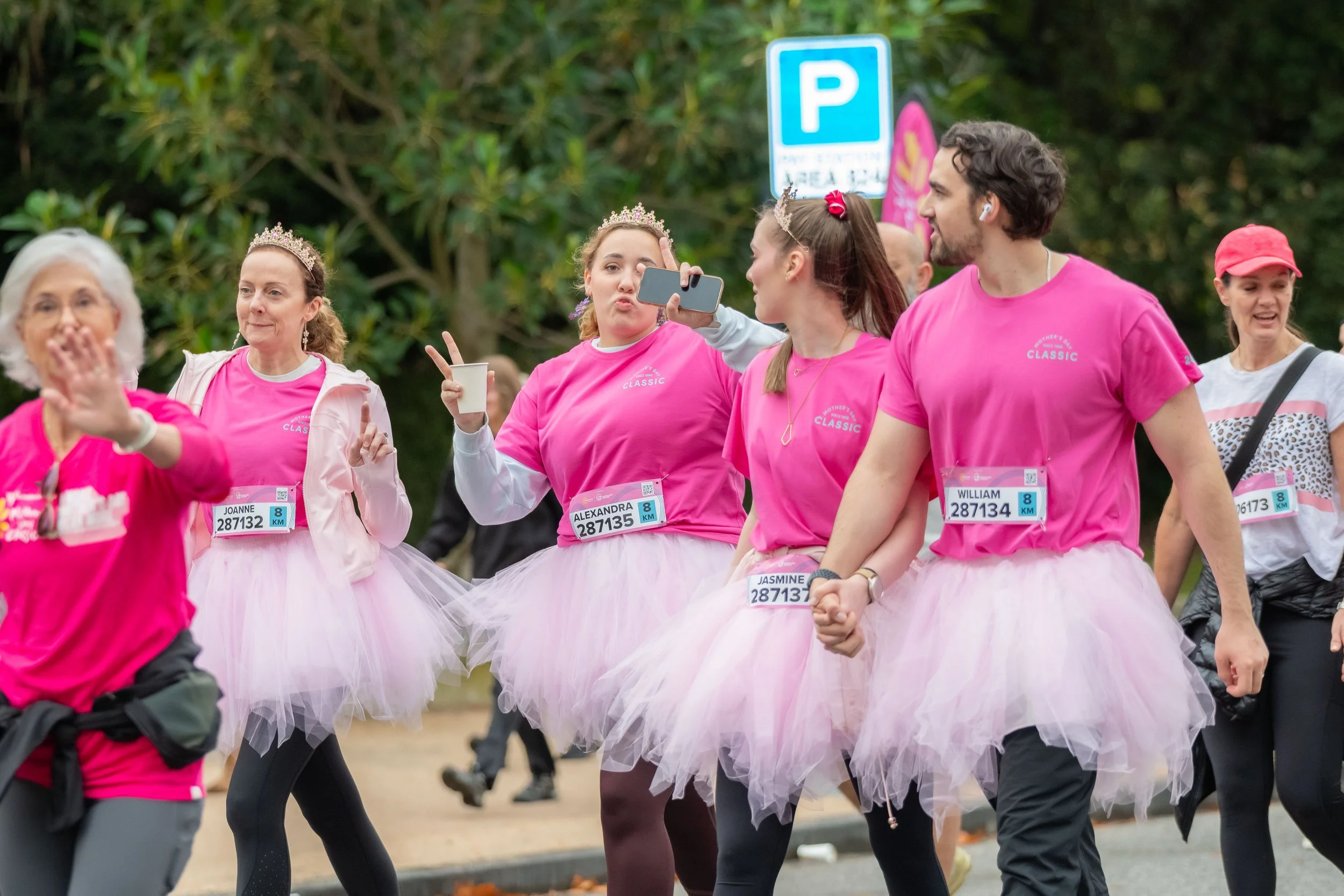 Four racegoers wear pink tees and tutus.