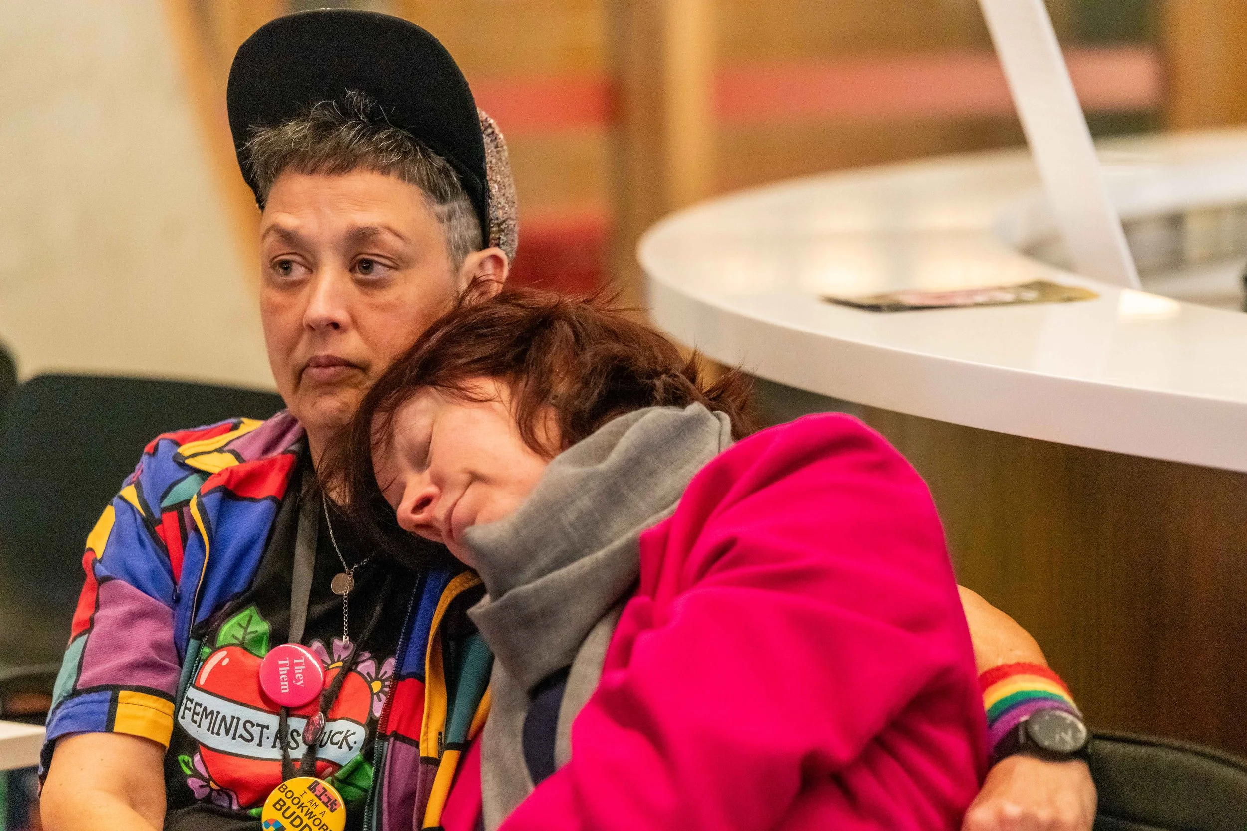 A human sleeps on the shoulder of another.