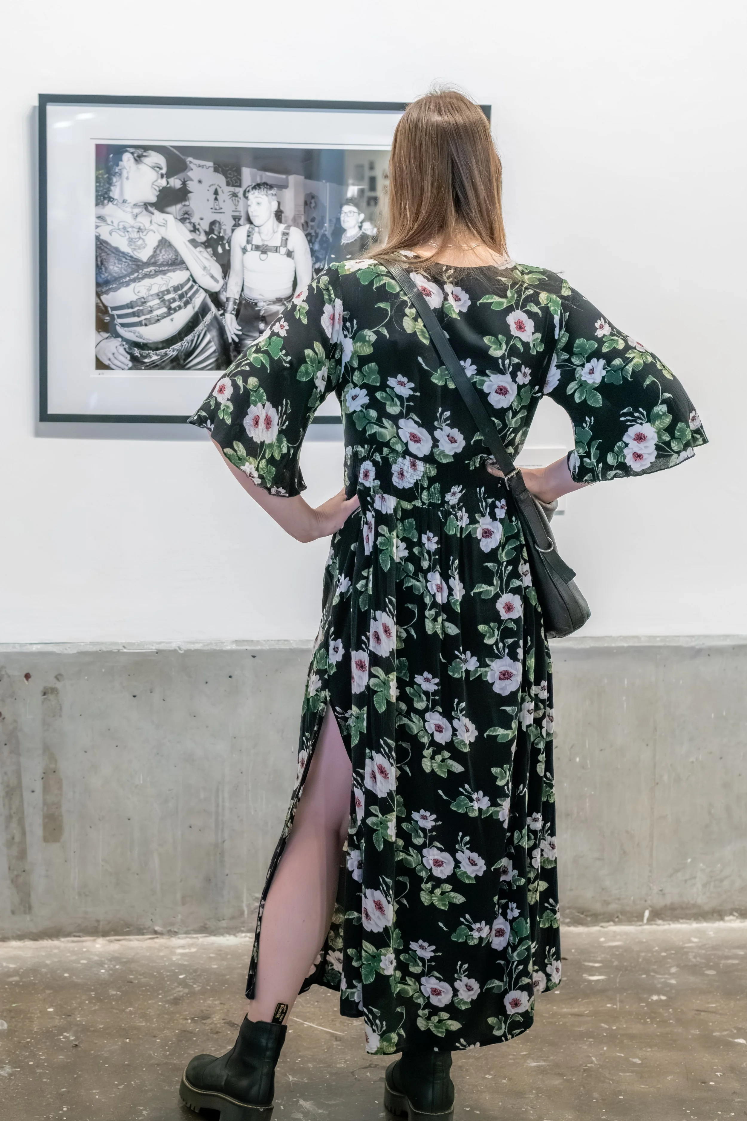 A human in a long flowing dress looks at a photograph.