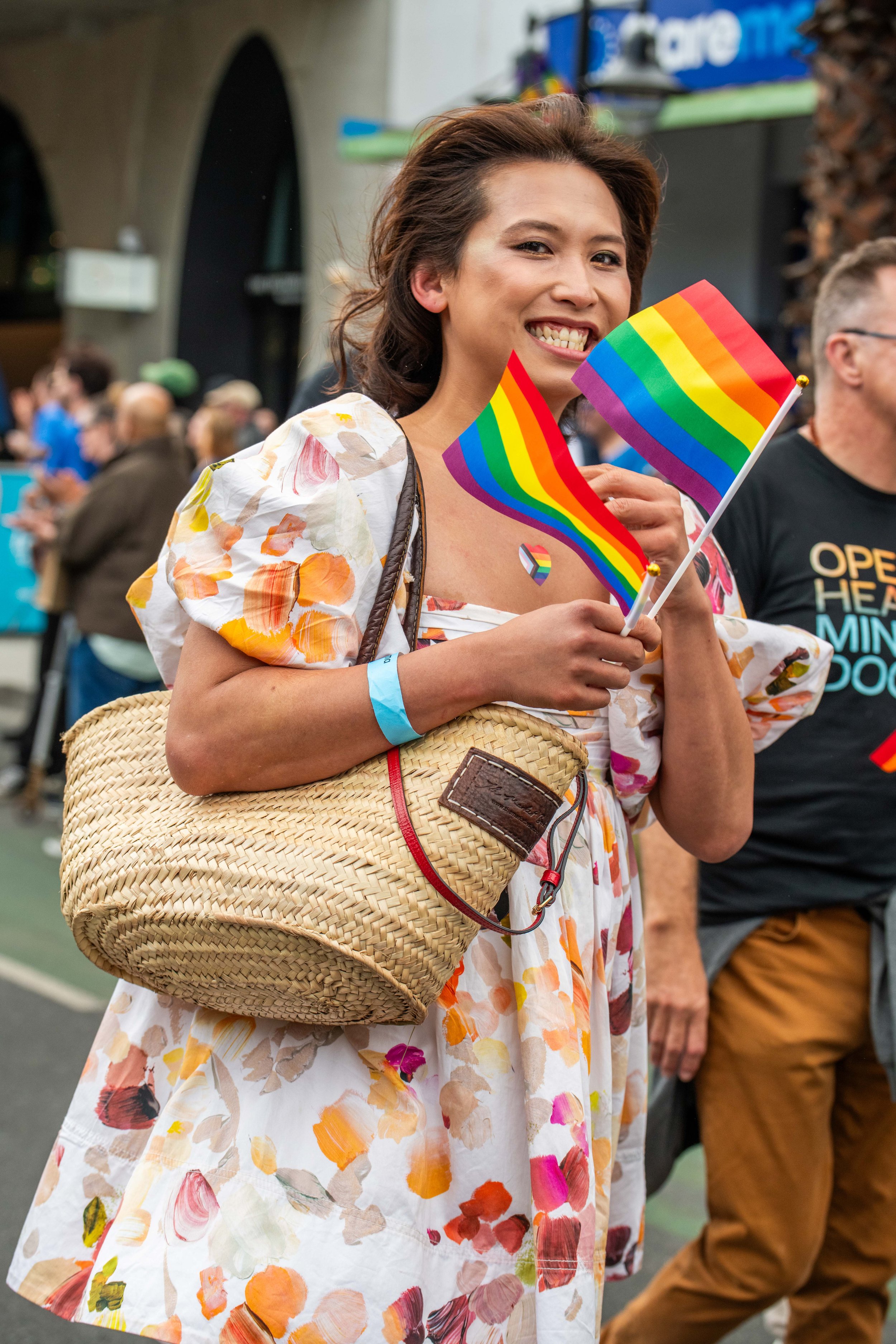 A human smiling and waving rainbow flags.