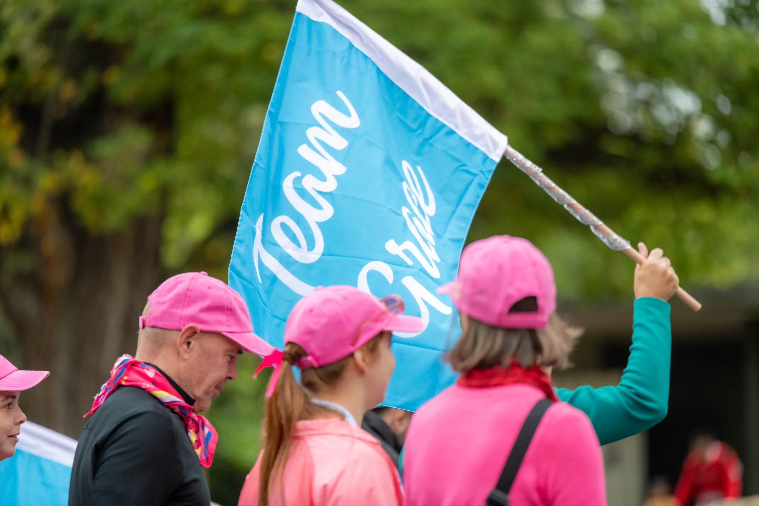 A racegoer holds up a blue flag with "Team Grace" written on it.