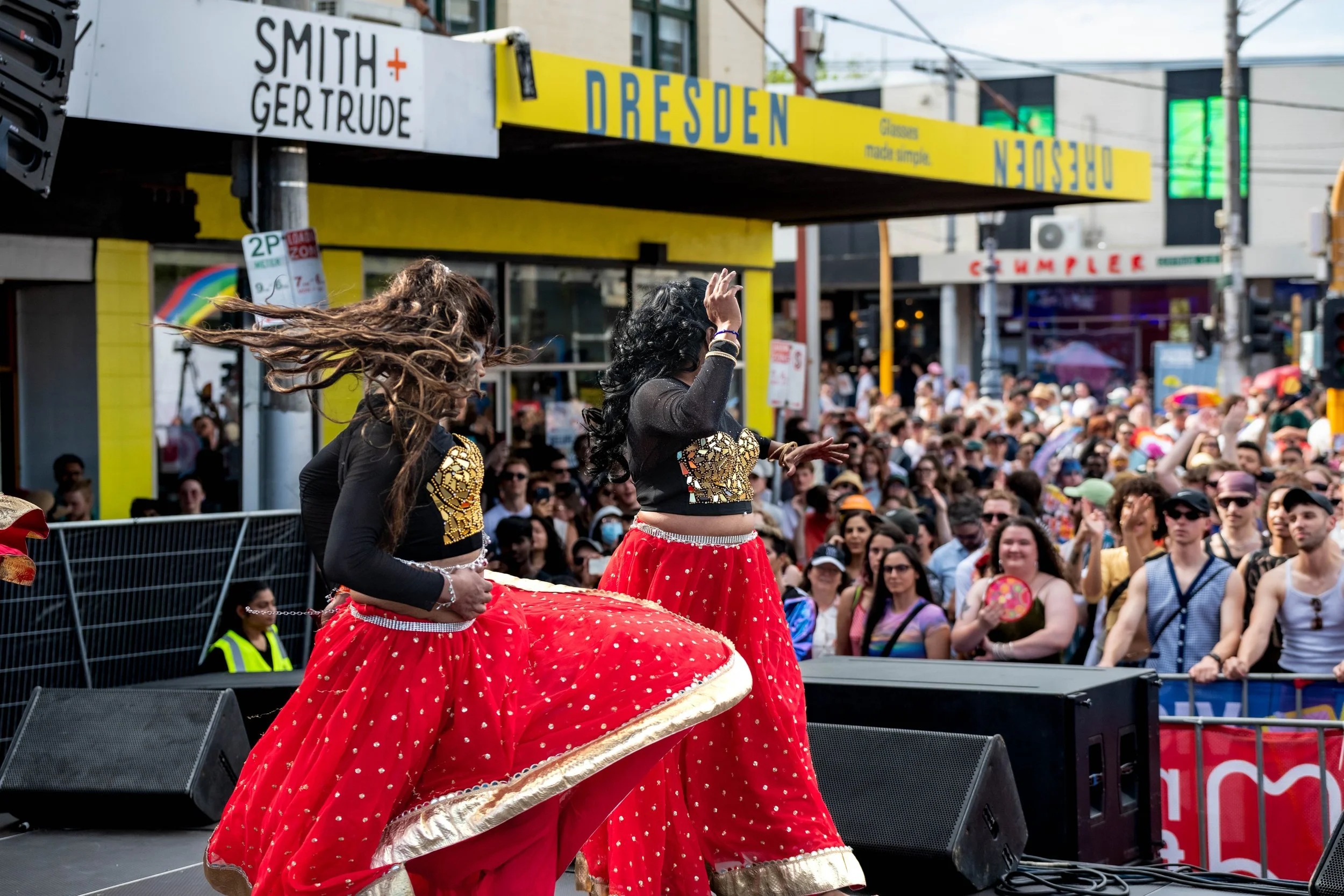 A dancer from Karma Dance whips their hair about as a large crowd look on.