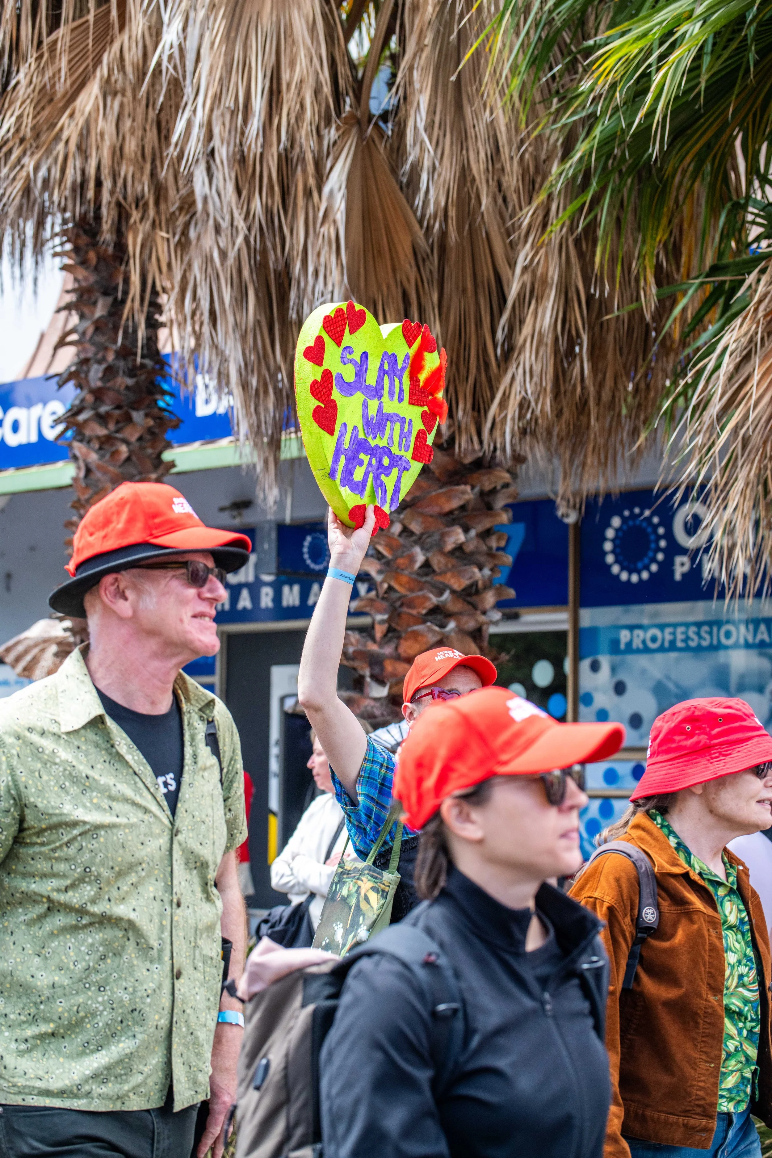 A human raises a love heart "Slay with heart".