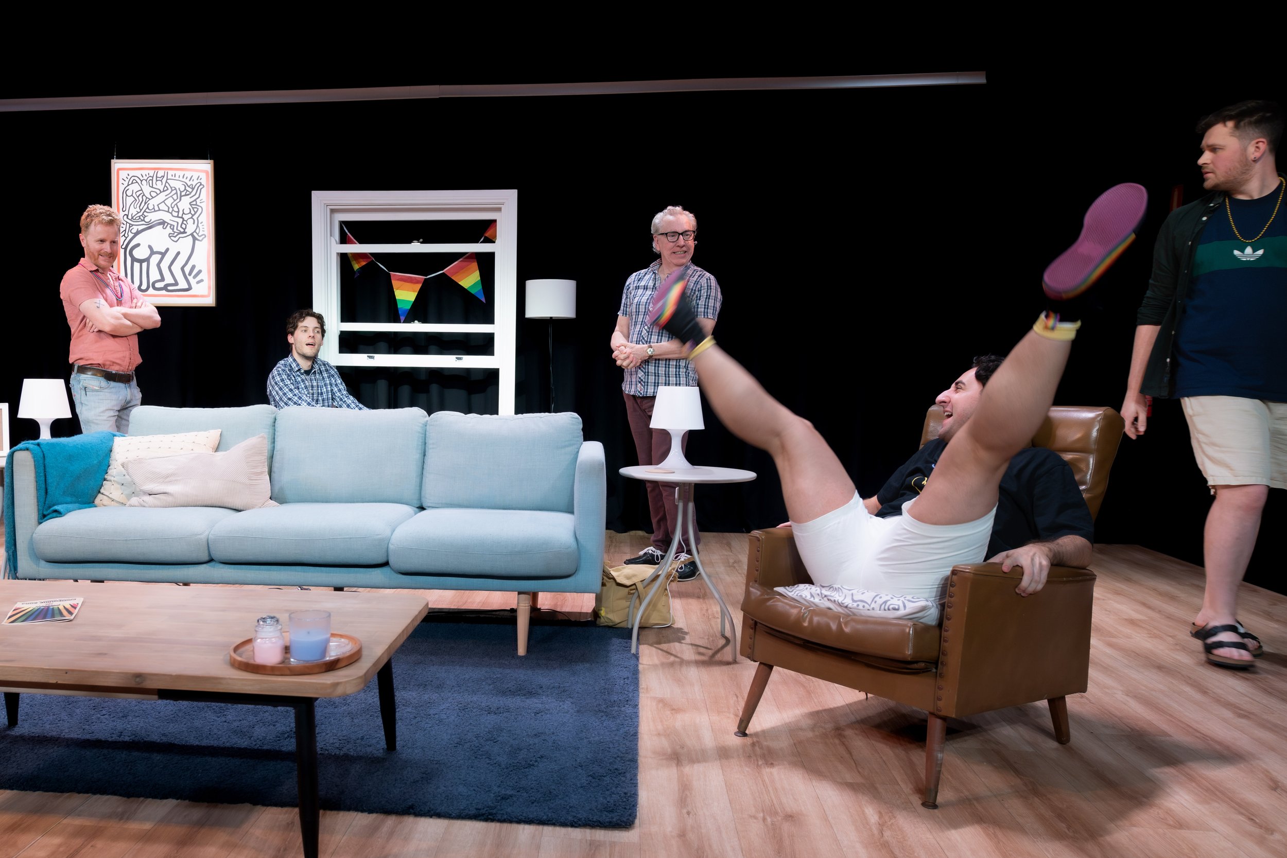 A human sits on a couch and spreads their legs high in the air.