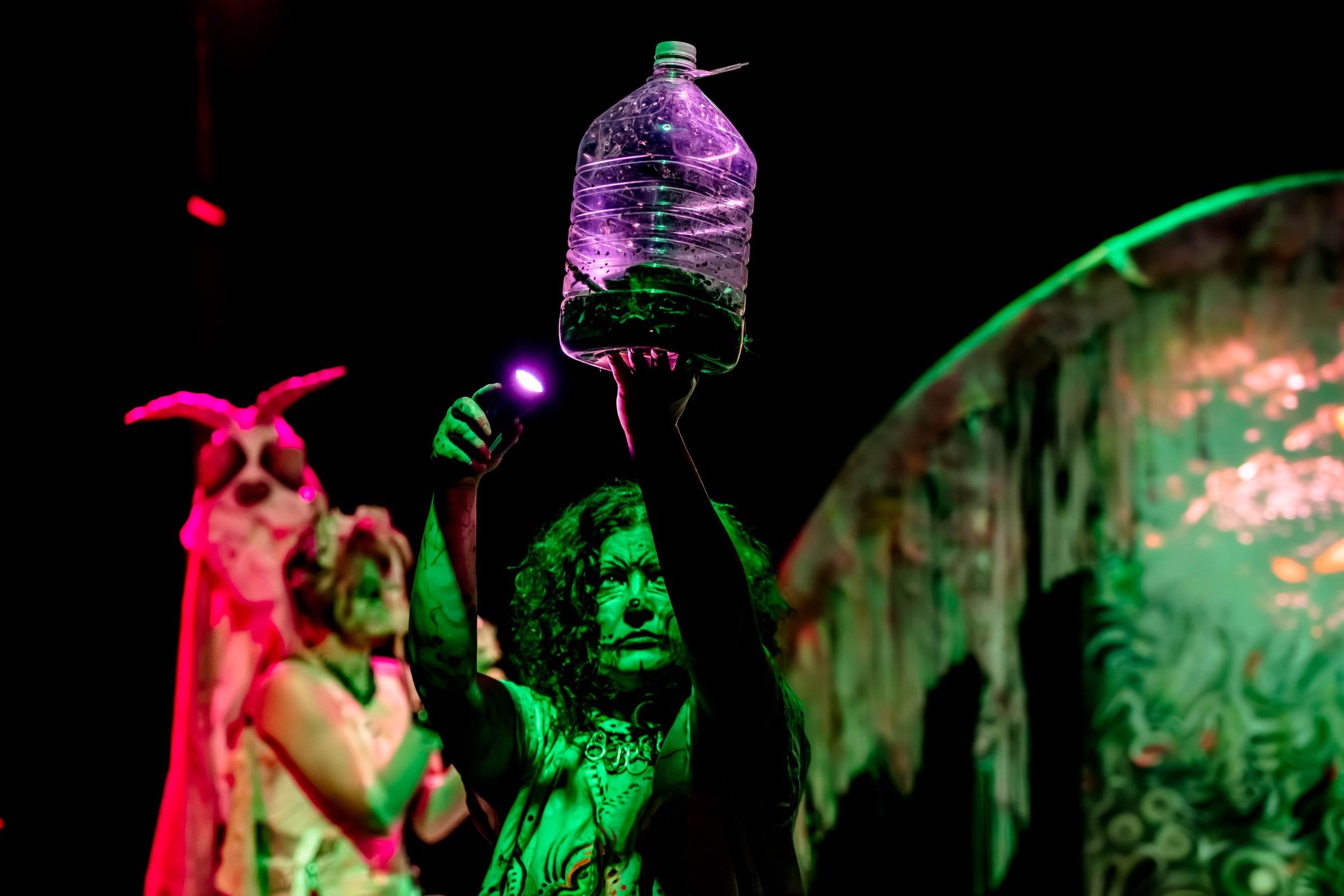 Jessie Ngaio holds aloft a jug of worms and shines a torch at it.