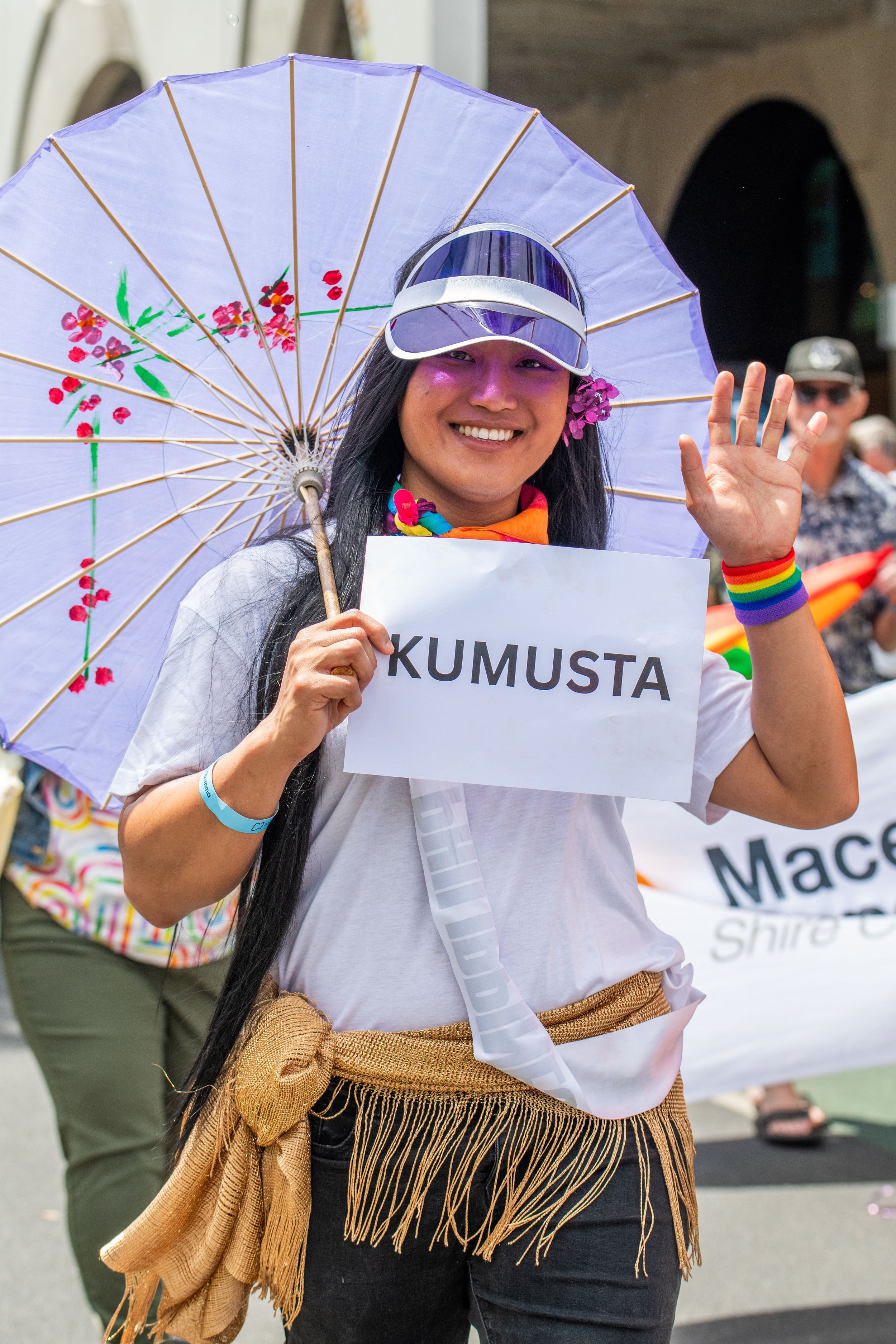 A human with a white parasol and a sign "Kumusta".