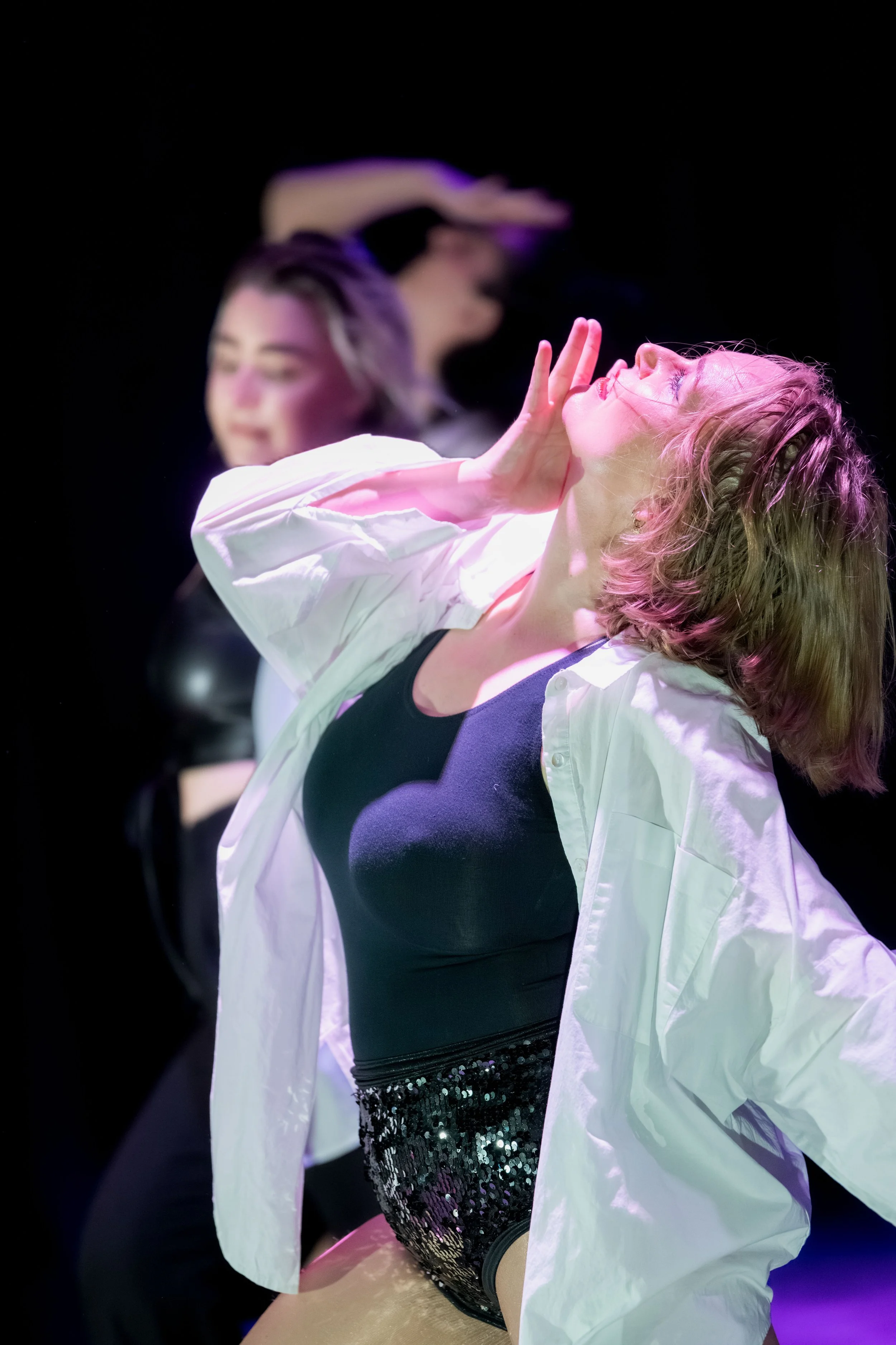 One dancer in black and white tilts their head back with their hand.