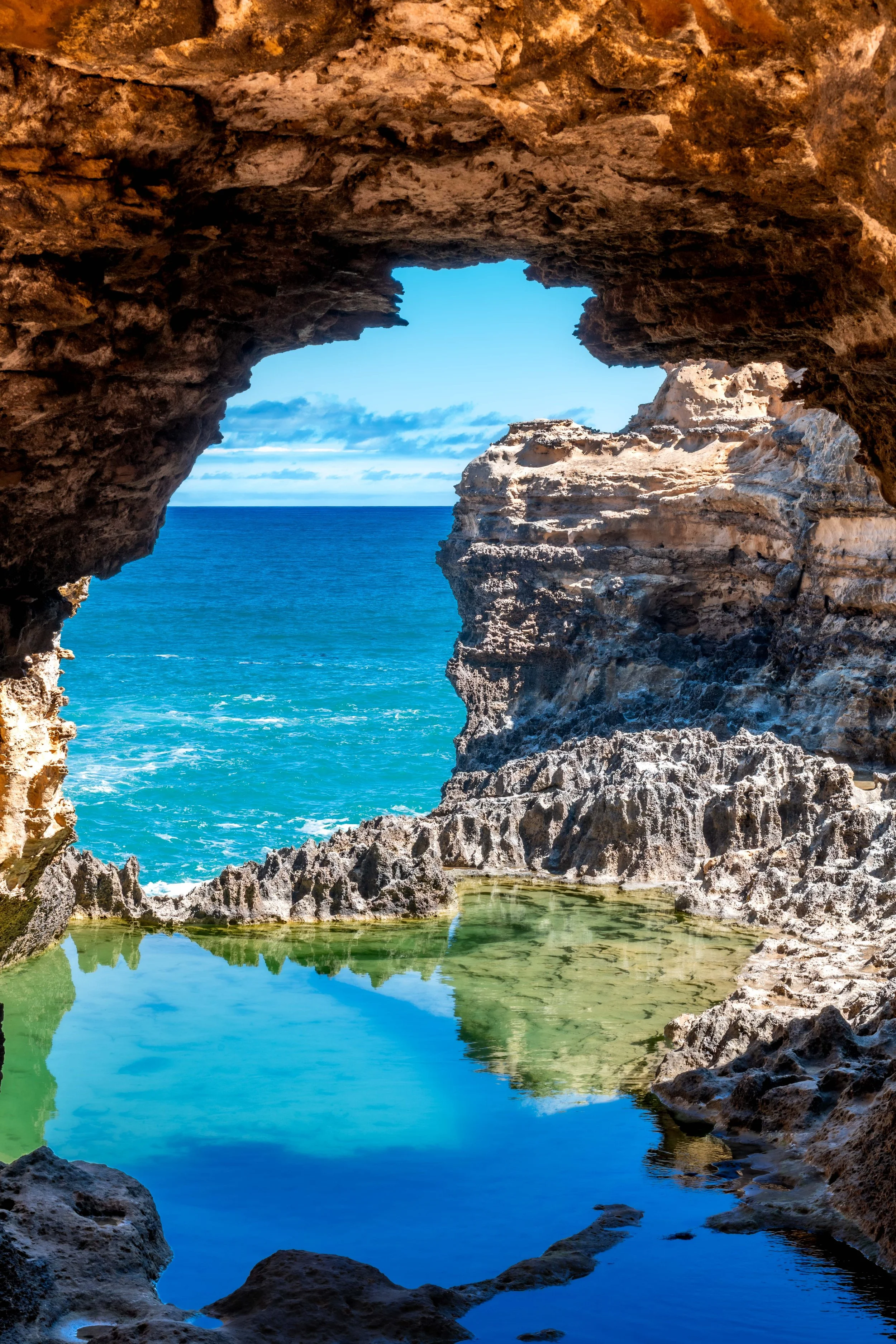 The ocean can be seen through a sandstone arch.