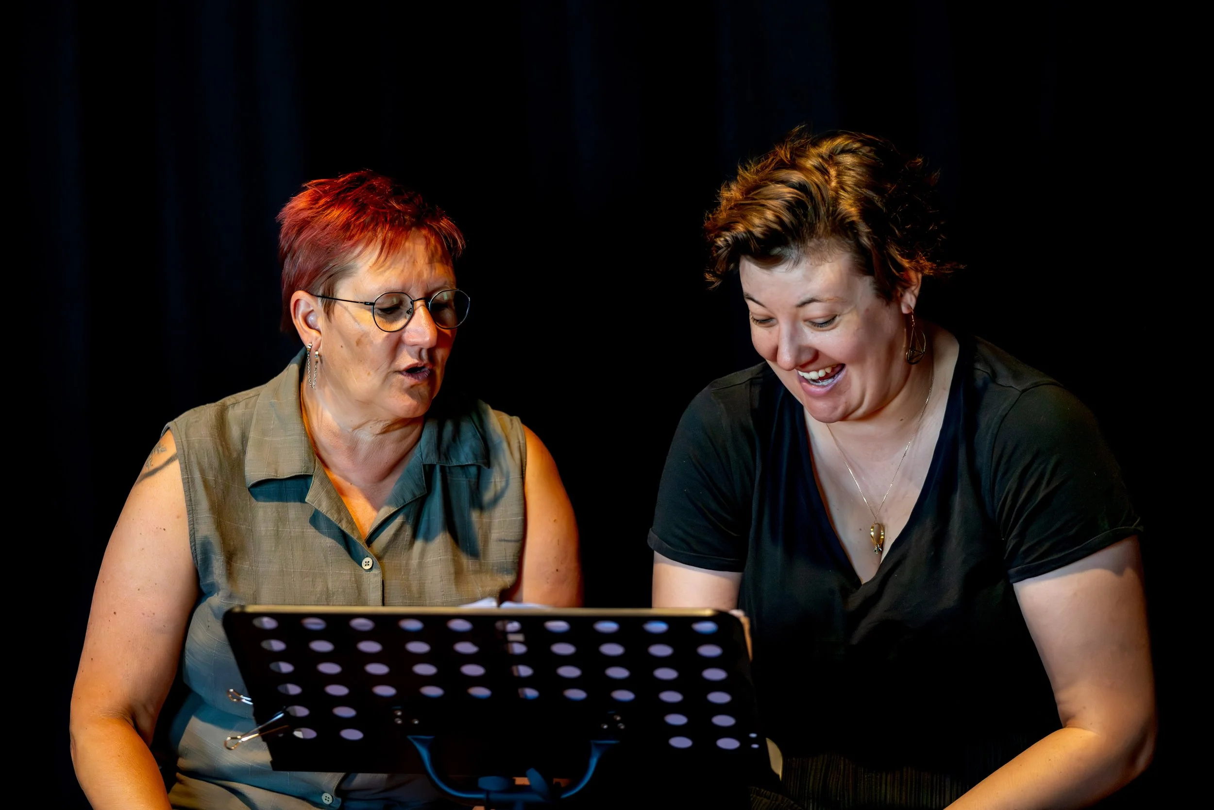 Two Auslan interpreters chatting and laughing.