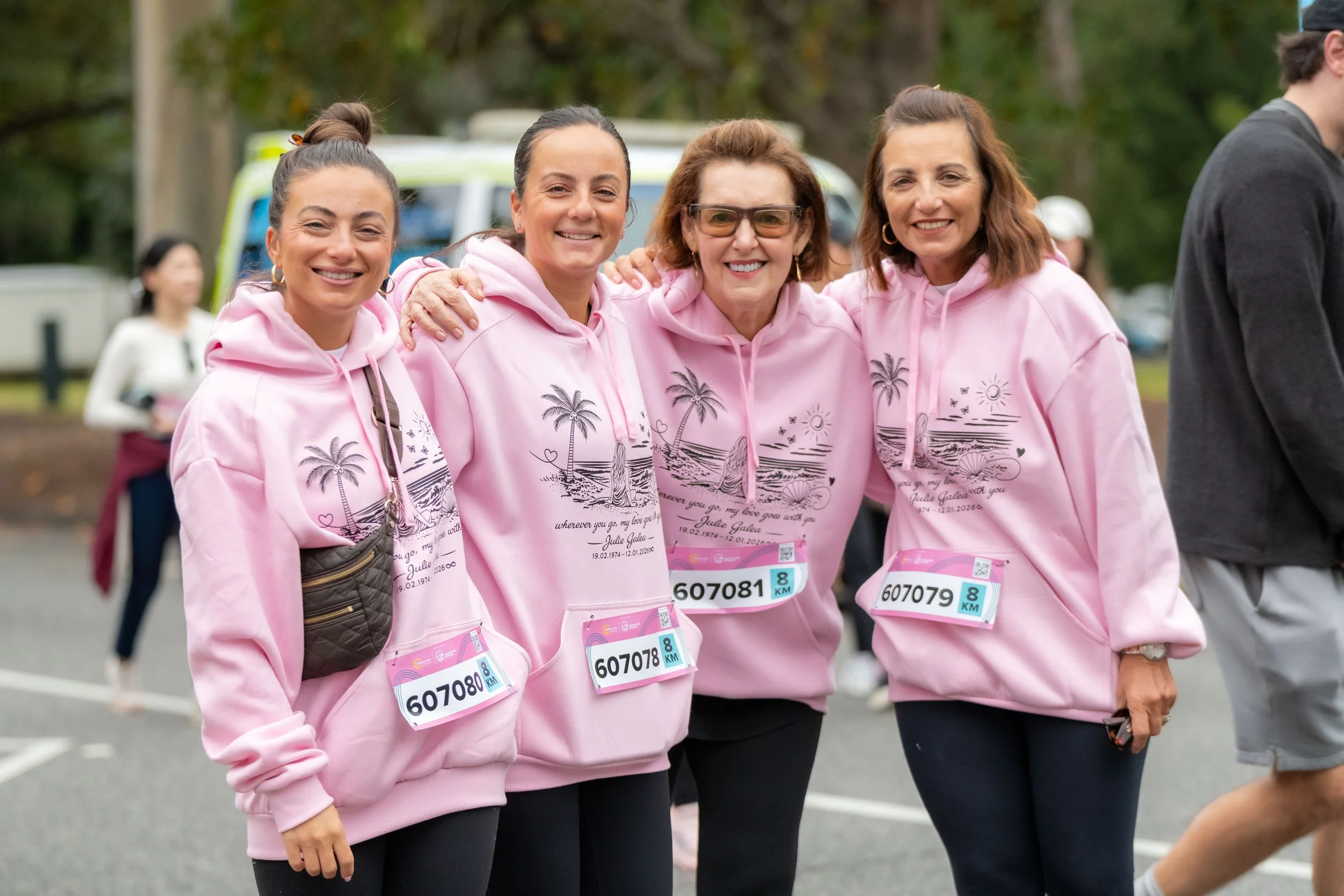 Four racegoers wearing mmeorial hoodies smile for the camera.