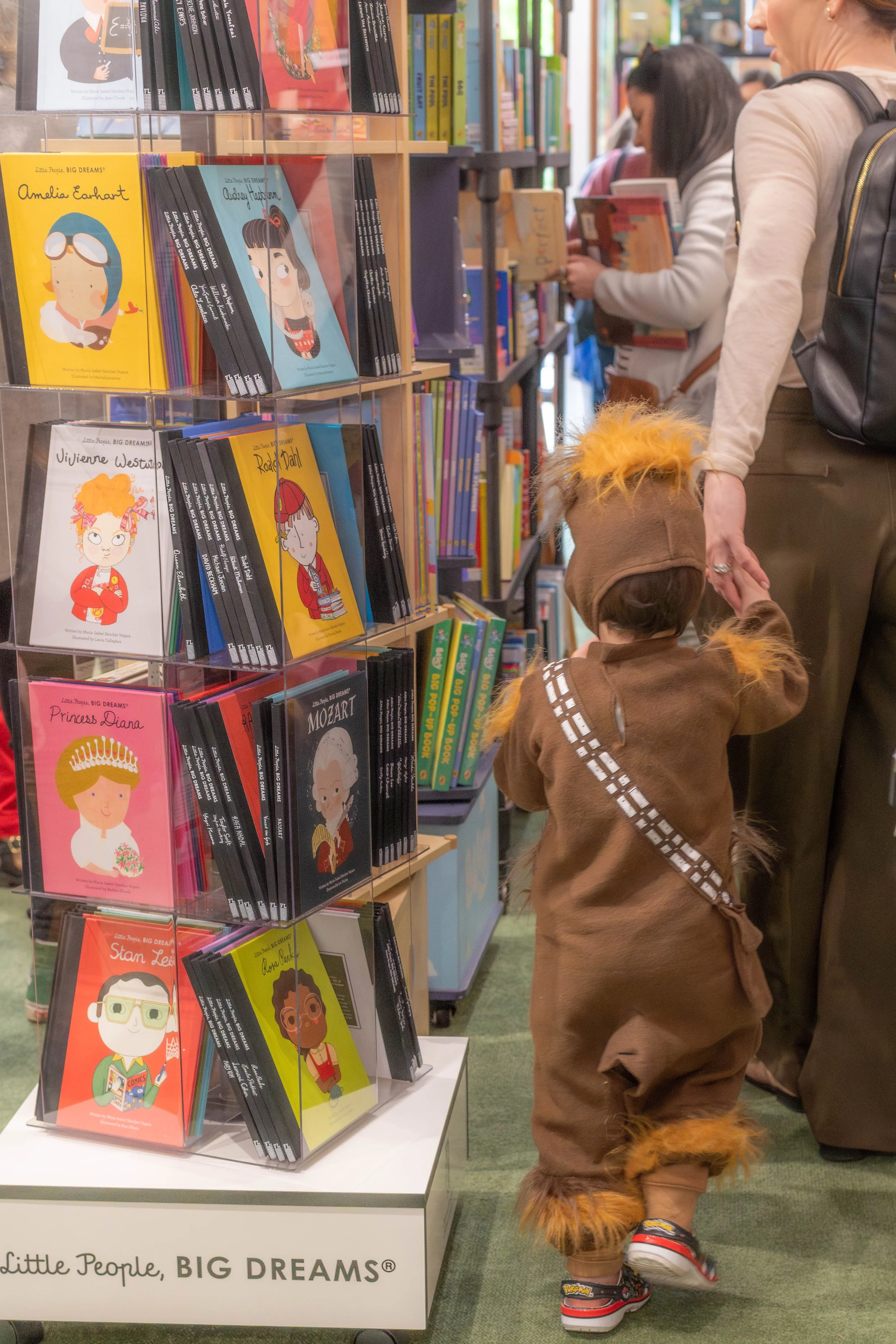 A child in a chewbacka costume is led by their parent.