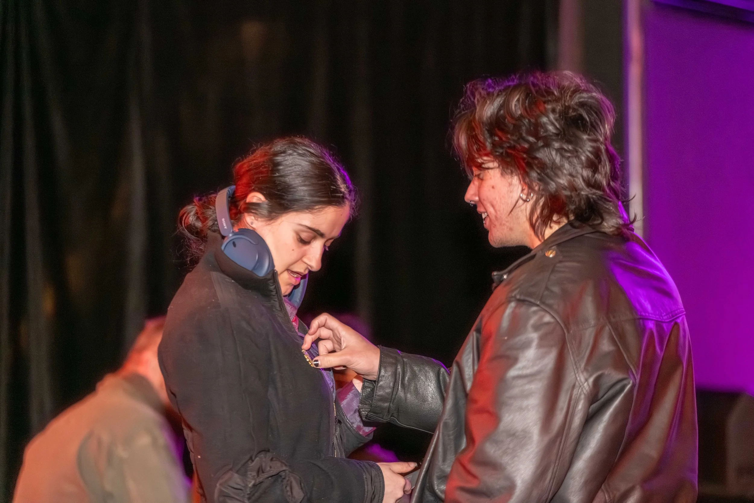 A human touches a badge on the top of another human.