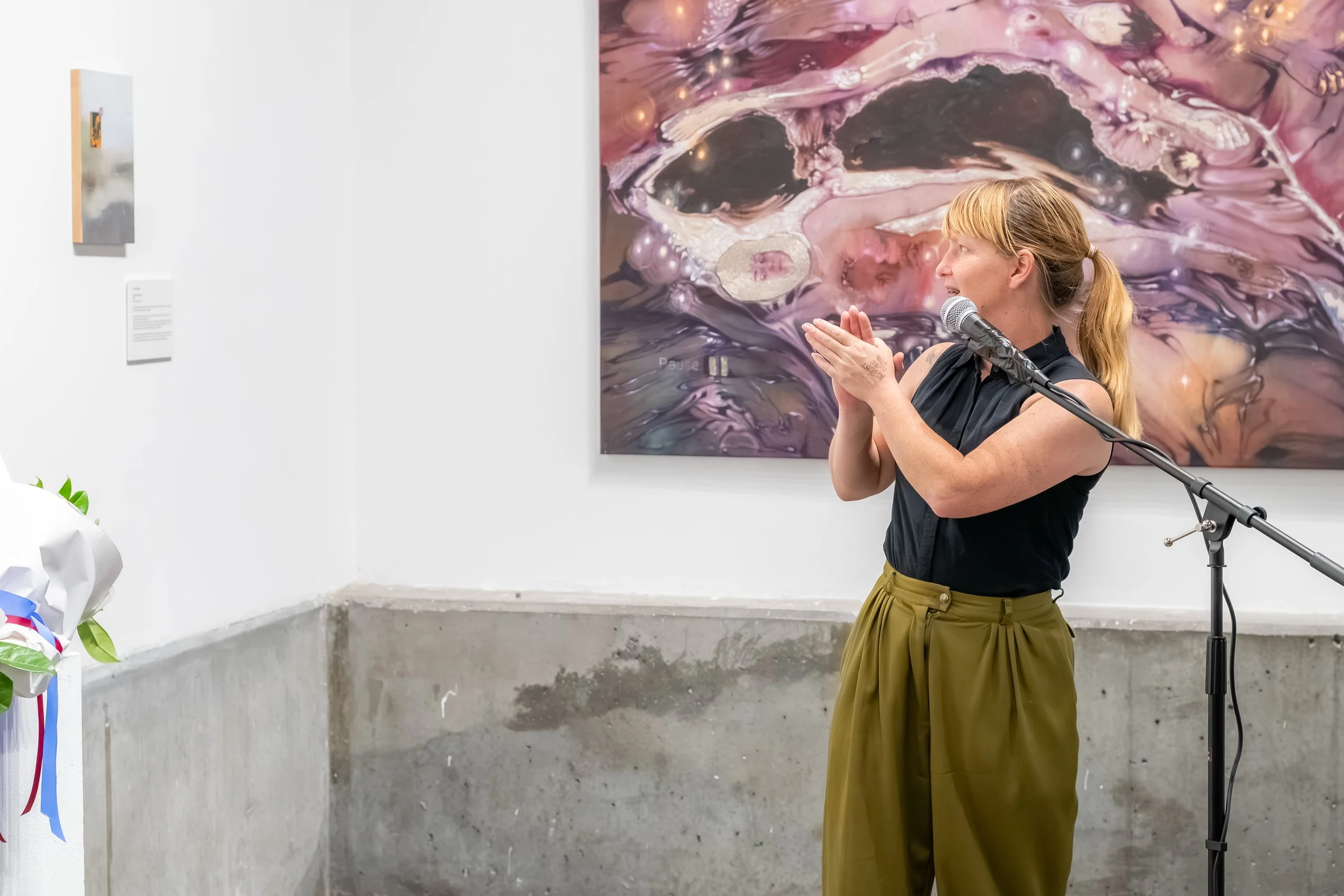 A human turns to a winning artwork whilst clapping.