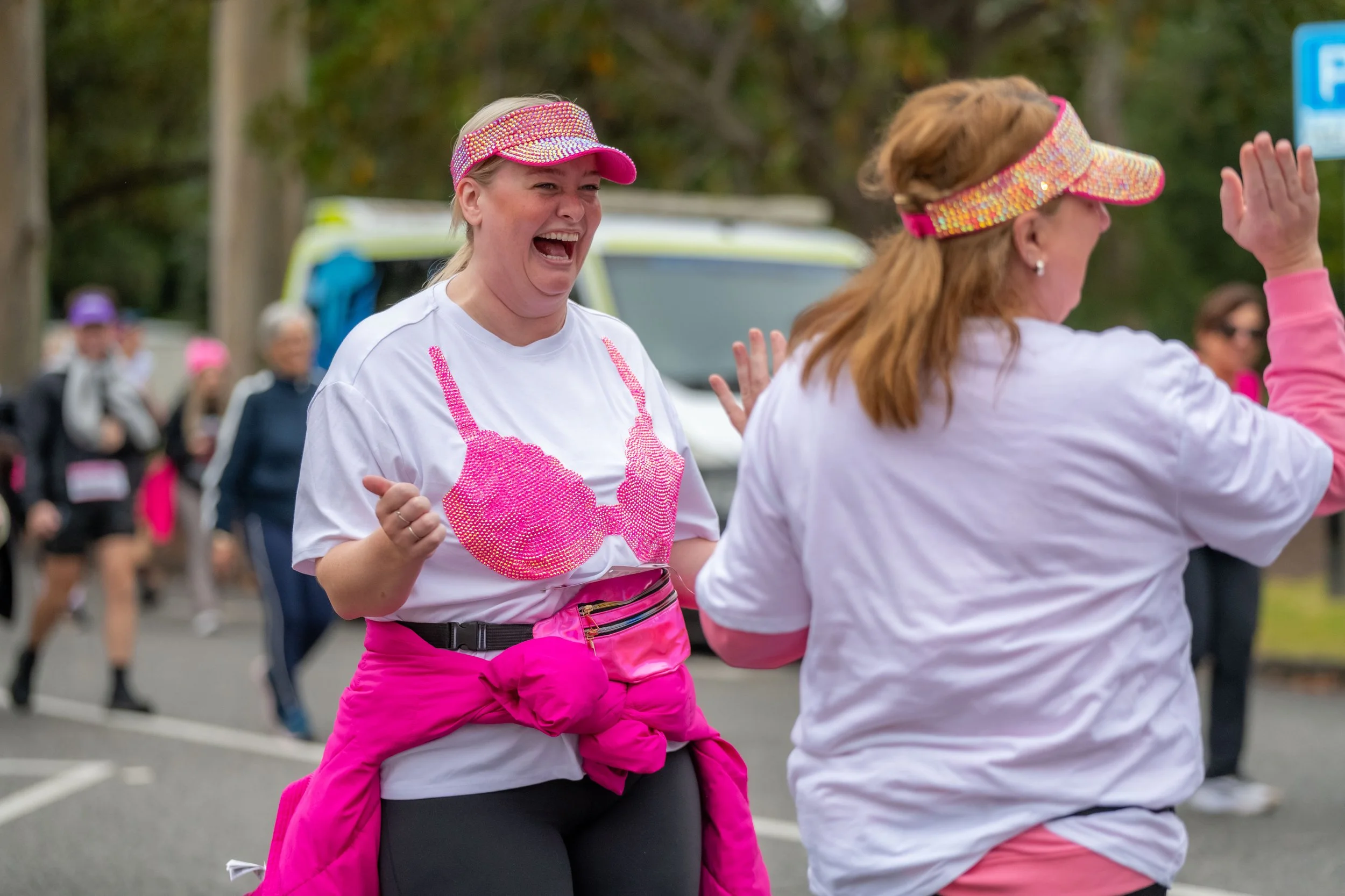 A racegoer in a white tee with a sparkly bra print on it dances.