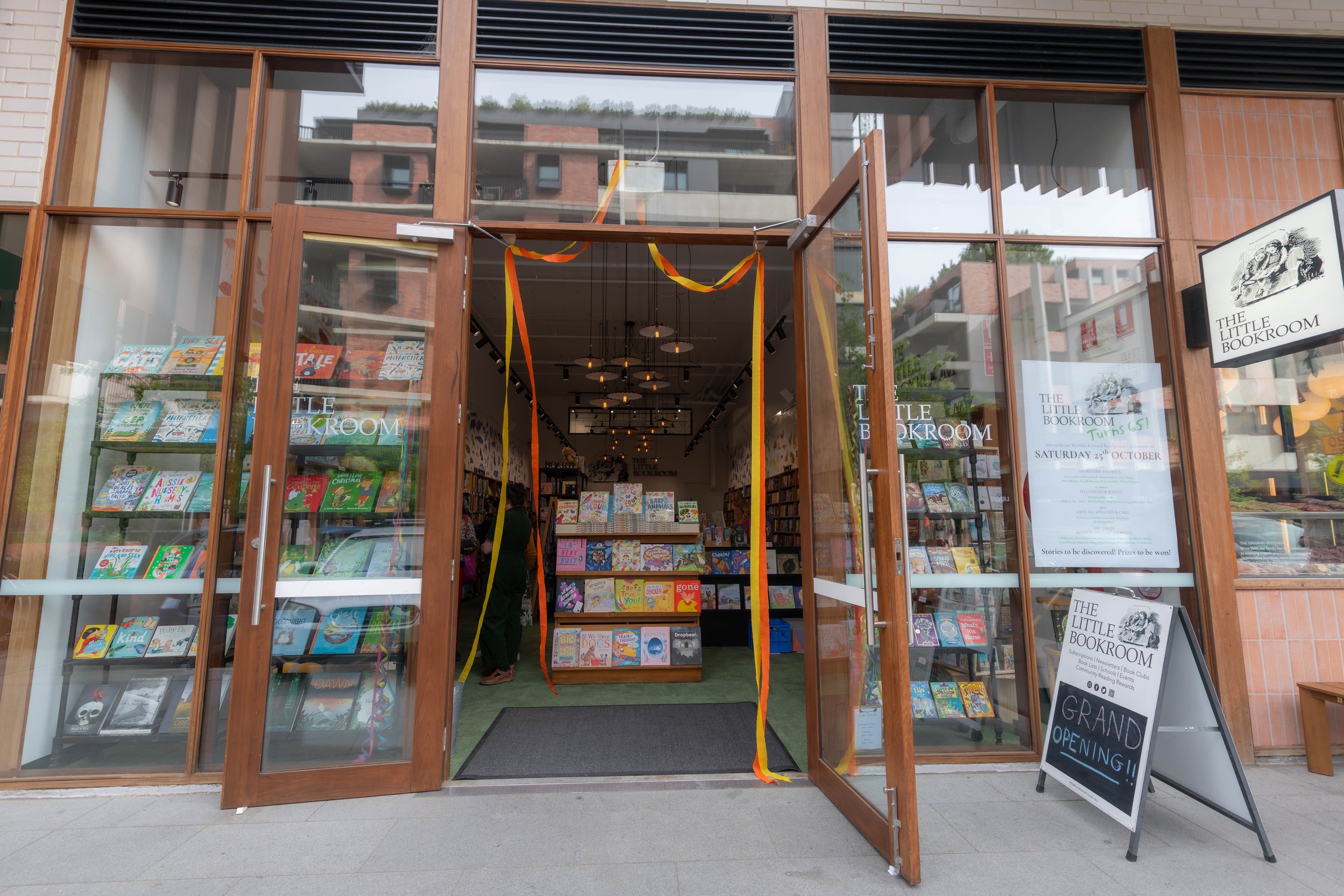 The outside of The Little Bookroom. Its glass doors are open and streamers are hanging down.