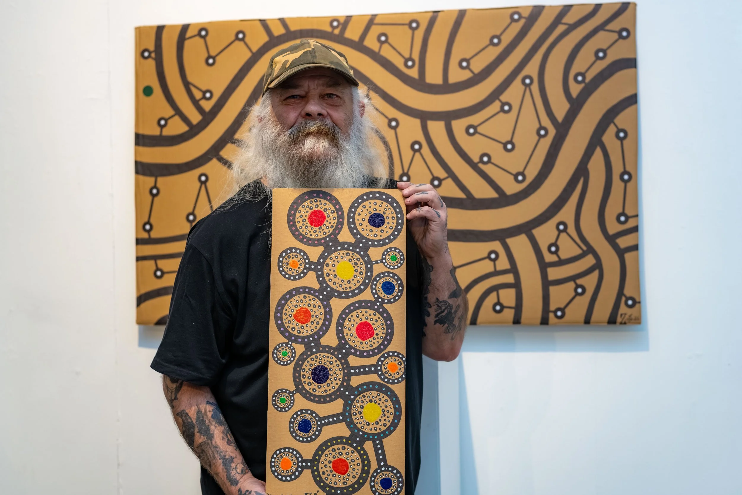 Laurence Flegg poses with two of their paintings.
