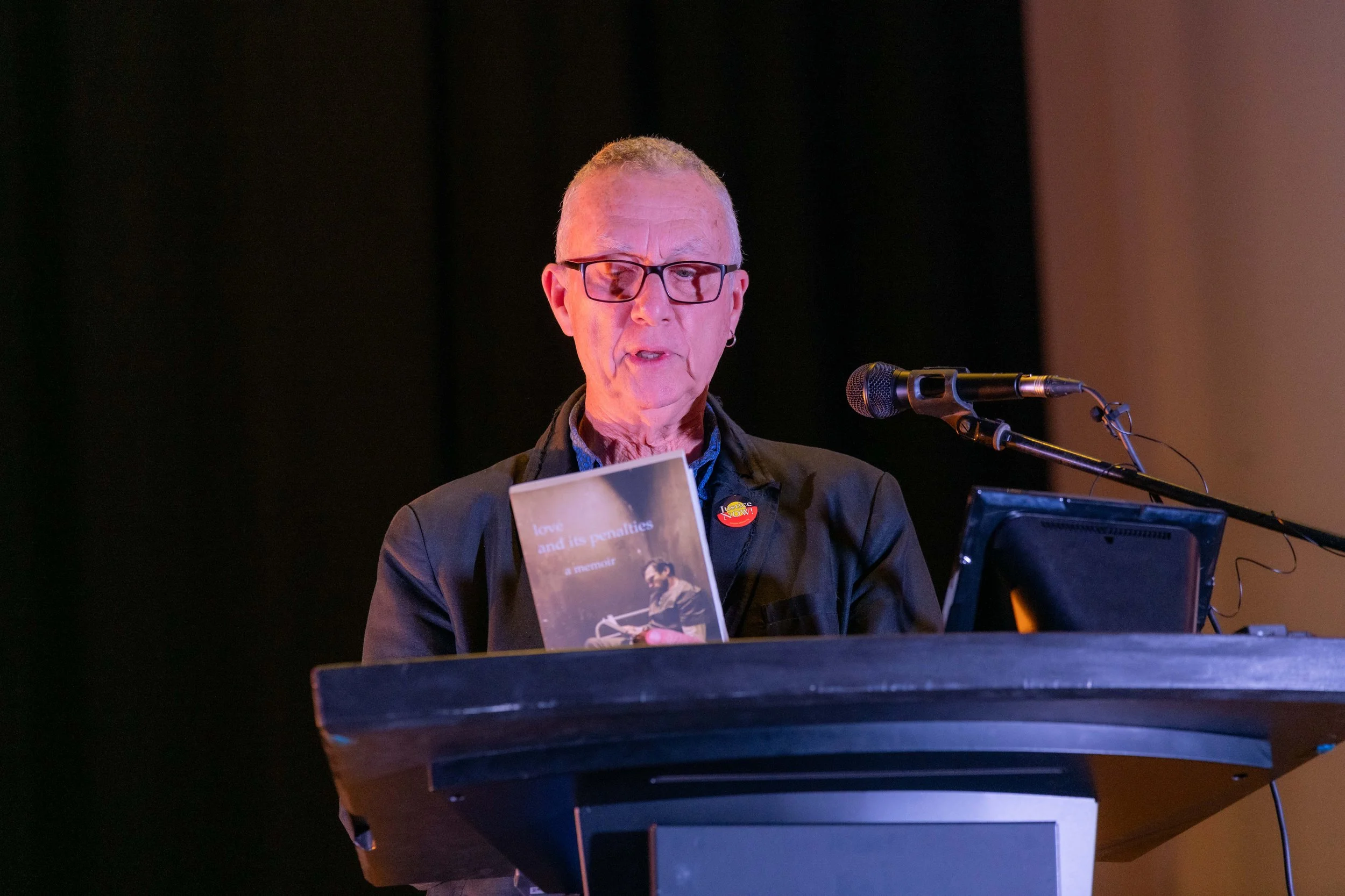 John Bartlett looks down at a book he is holding up.