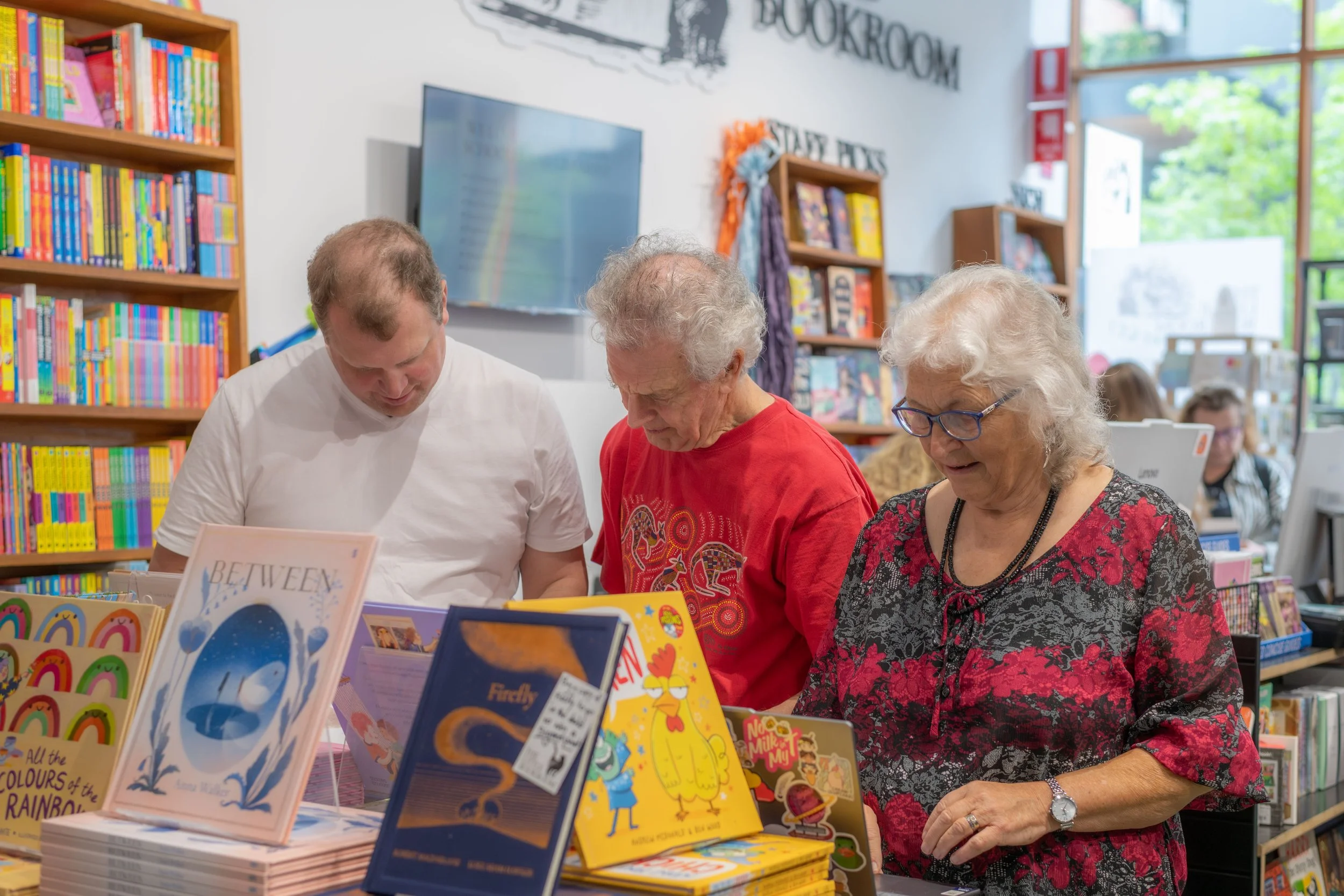 Three humans look down at a display of books. This is Michael Earp's parents and one of their brothers.