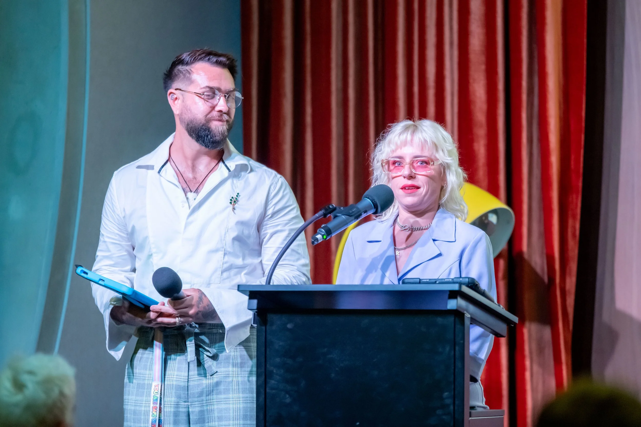 Two humans stand at a lecturn.