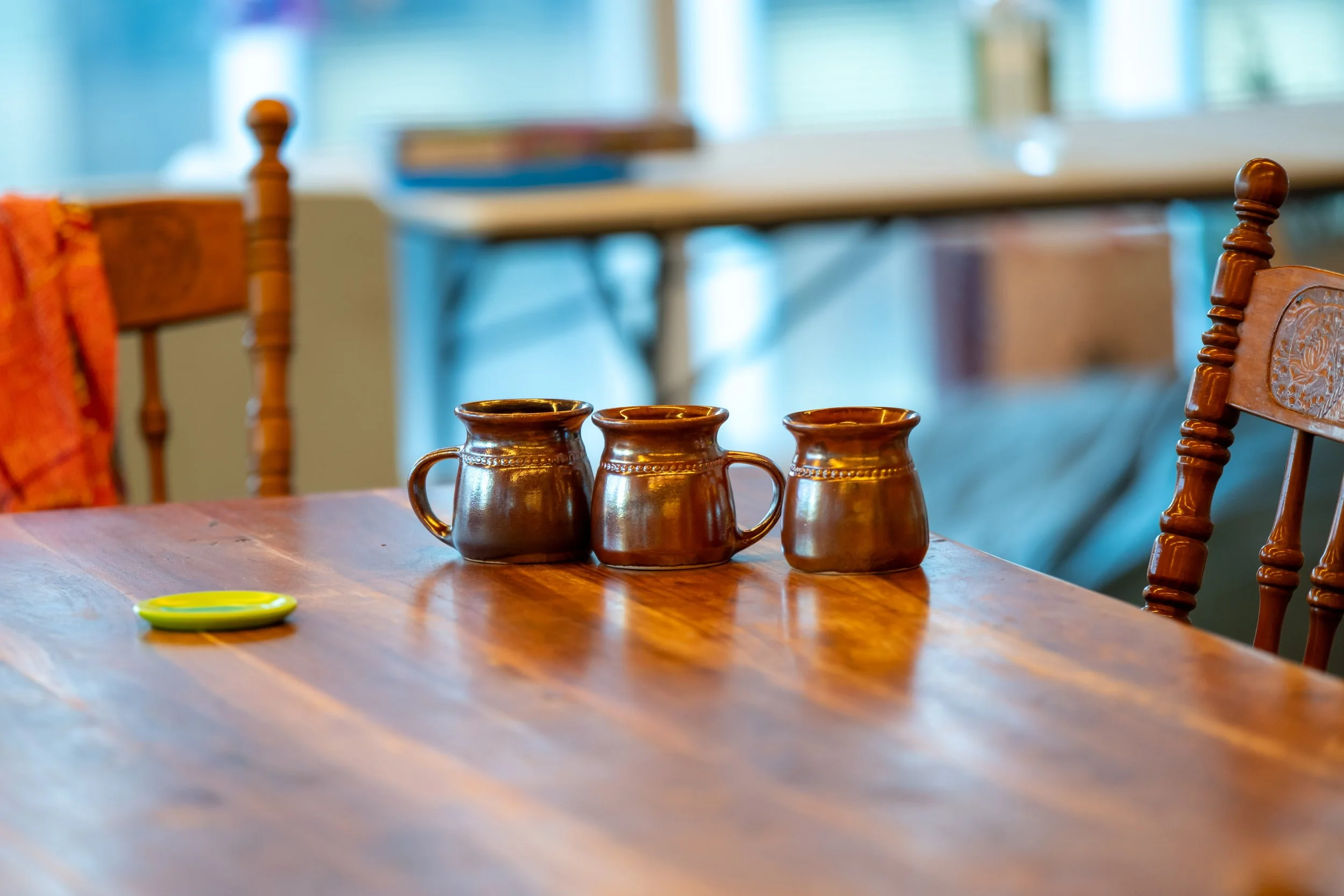 Three brown mugs sit on a wooden table.