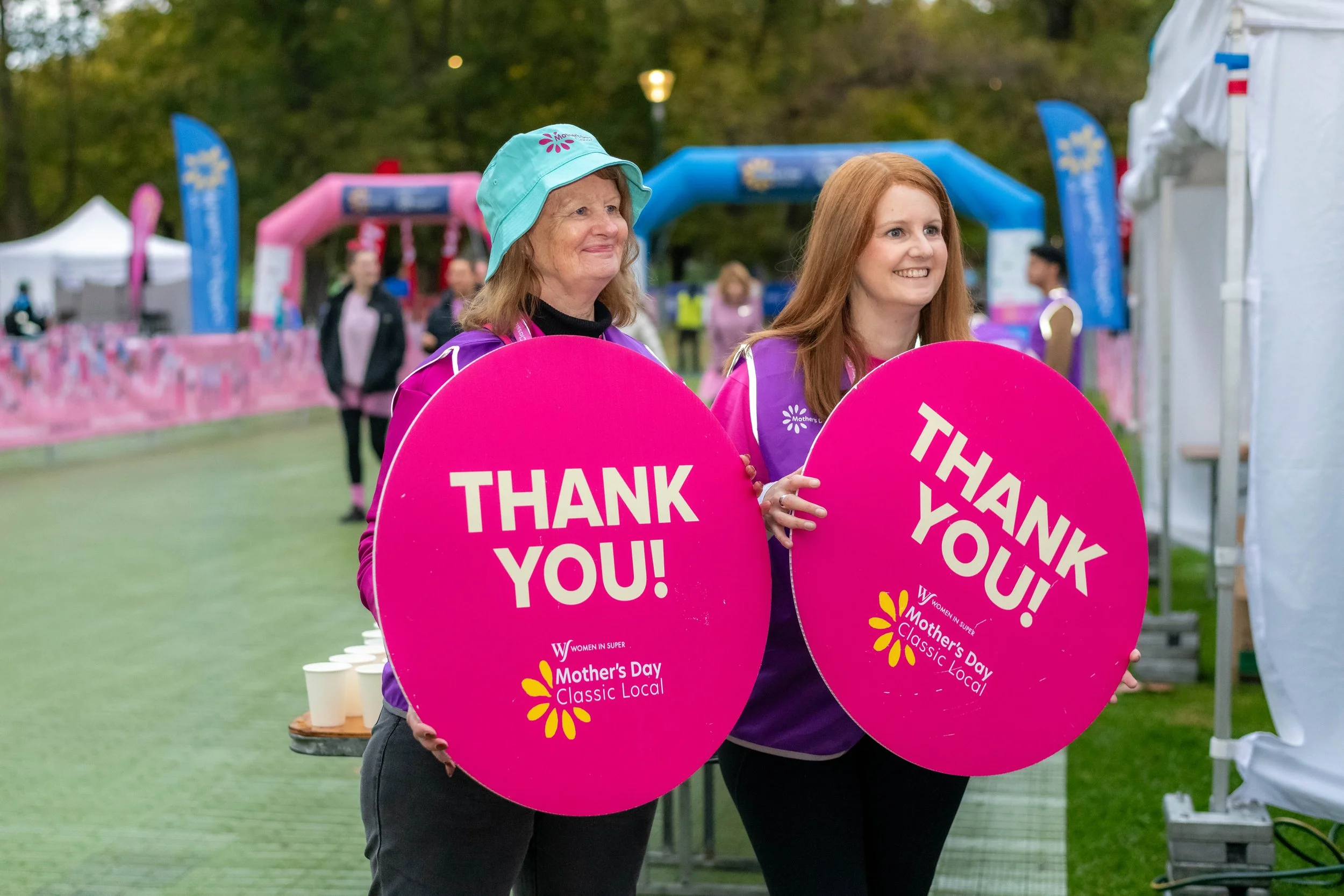 Two volunteers hold thank you signs.