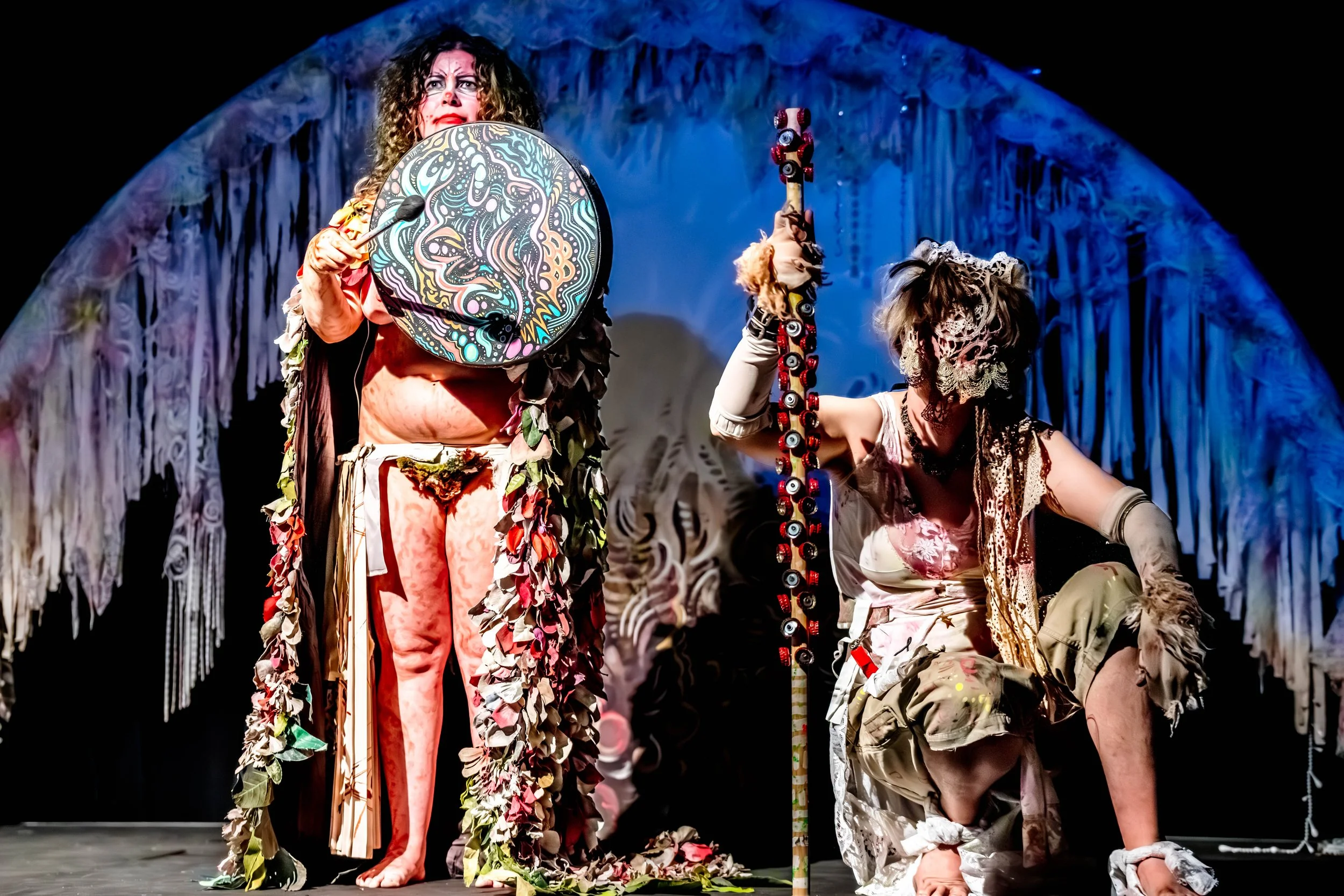 Jessie Ngaio bangs an ornately painted drum whilst Sian Horrocks crouches down nearby.