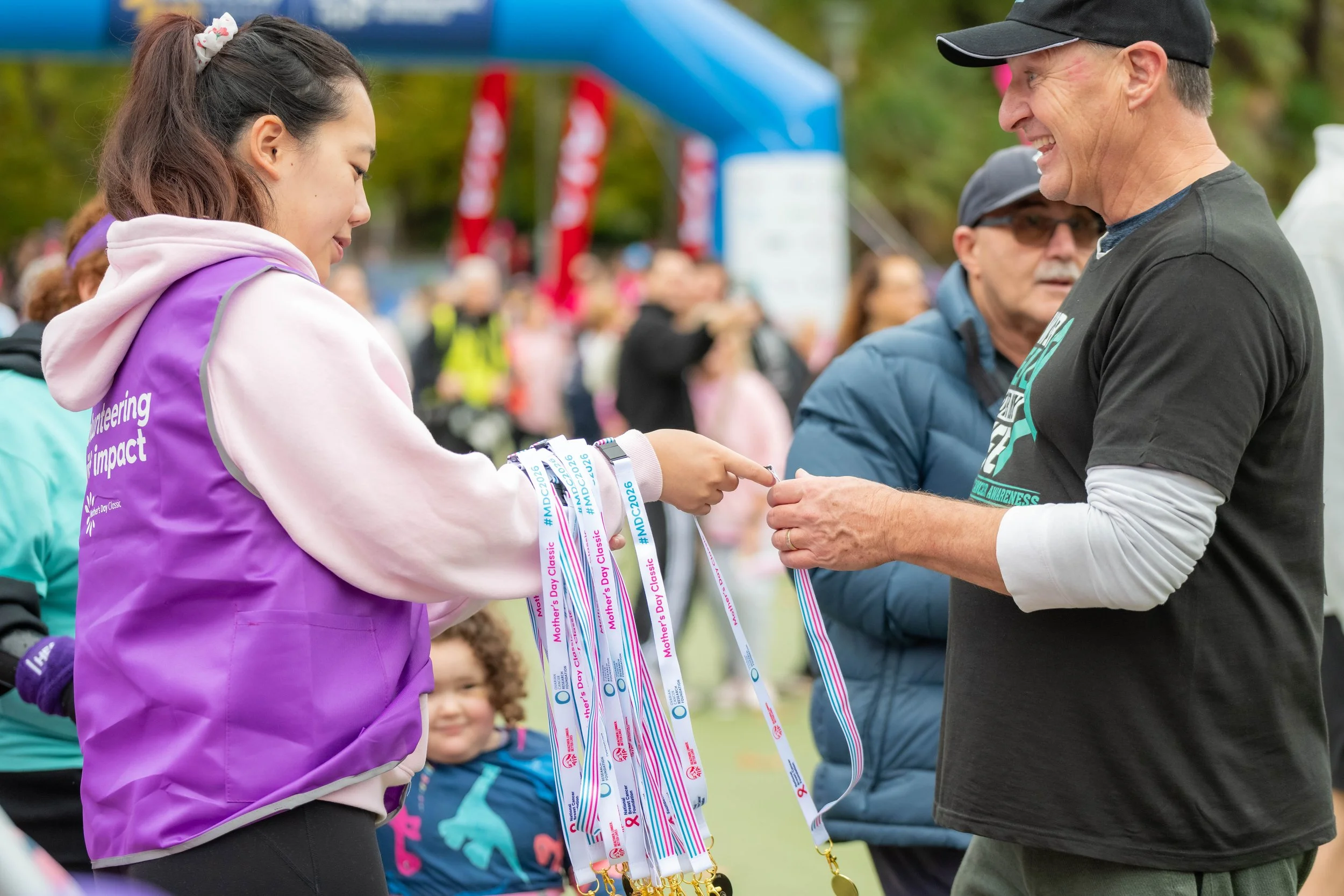 A volunteer hands a racegoer a medal.