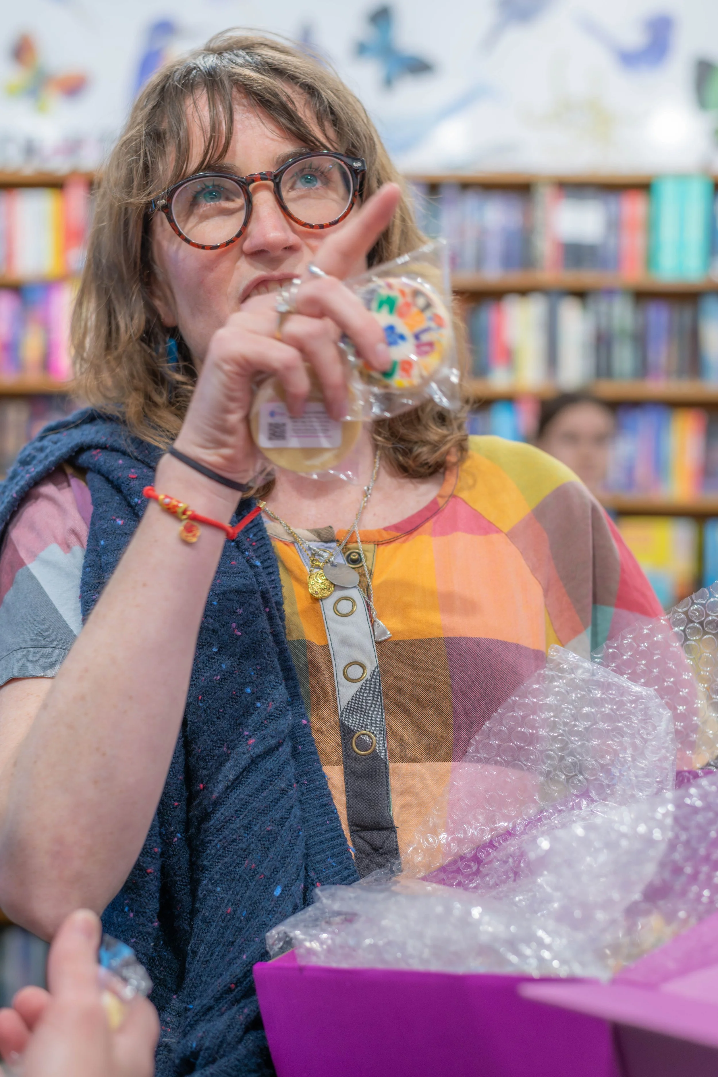 An illustrator holds up a rainbow cookie and points at something off camera.