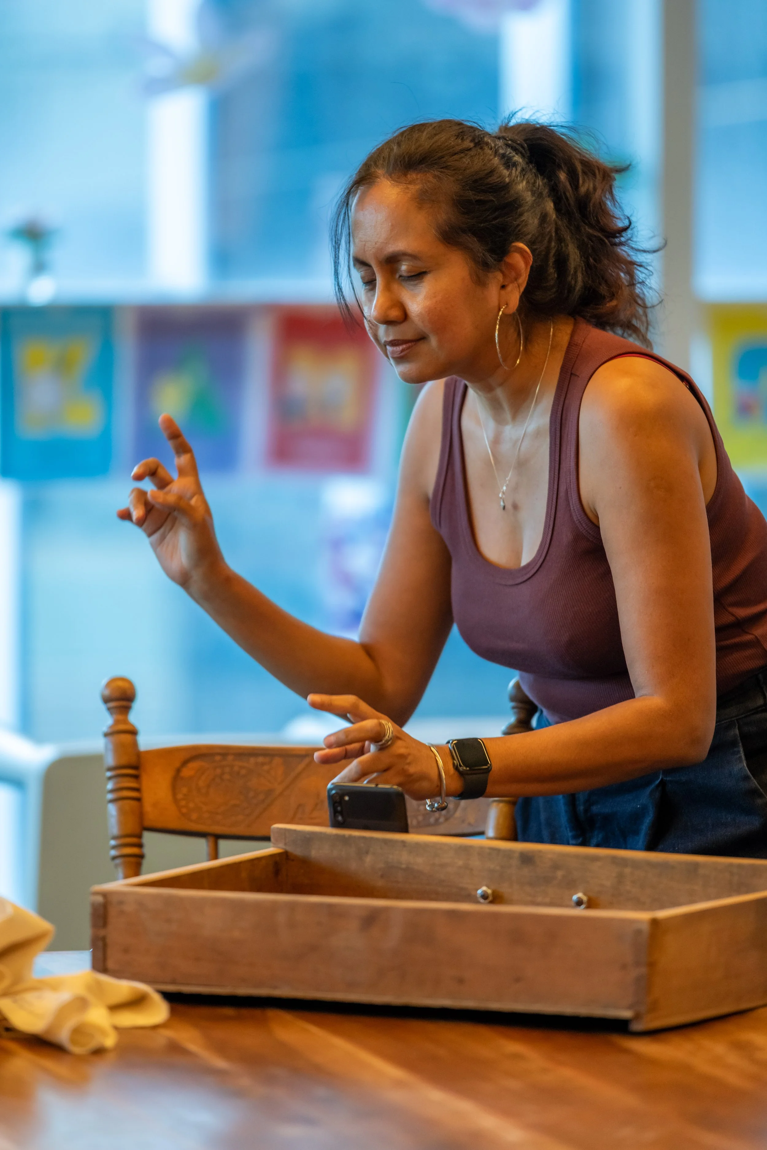 A human with their long hair pulled back has their eyes closed. Their hands are in the air as if conducting a symphony.