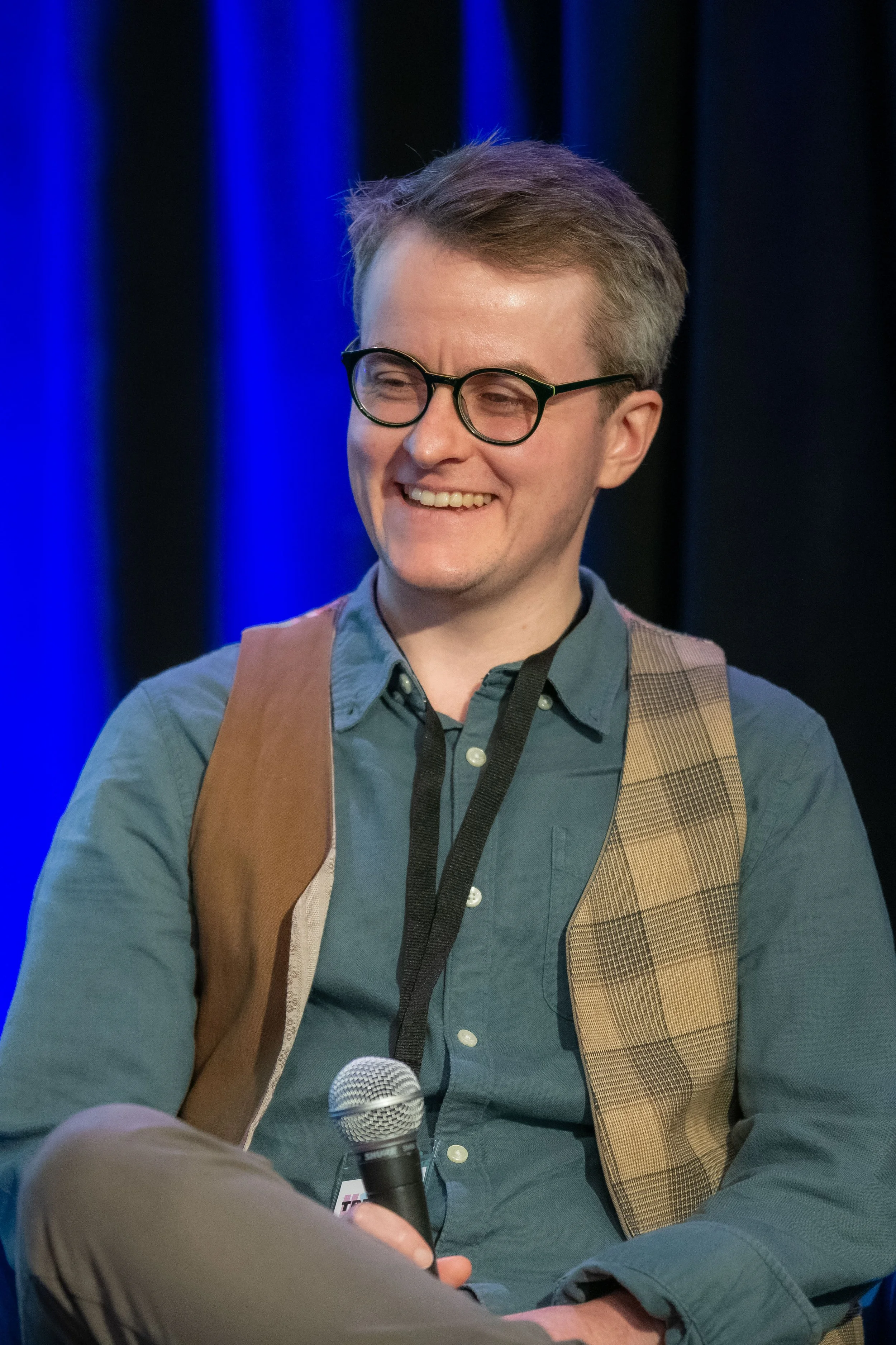 A panelist in black glasses laughs.
