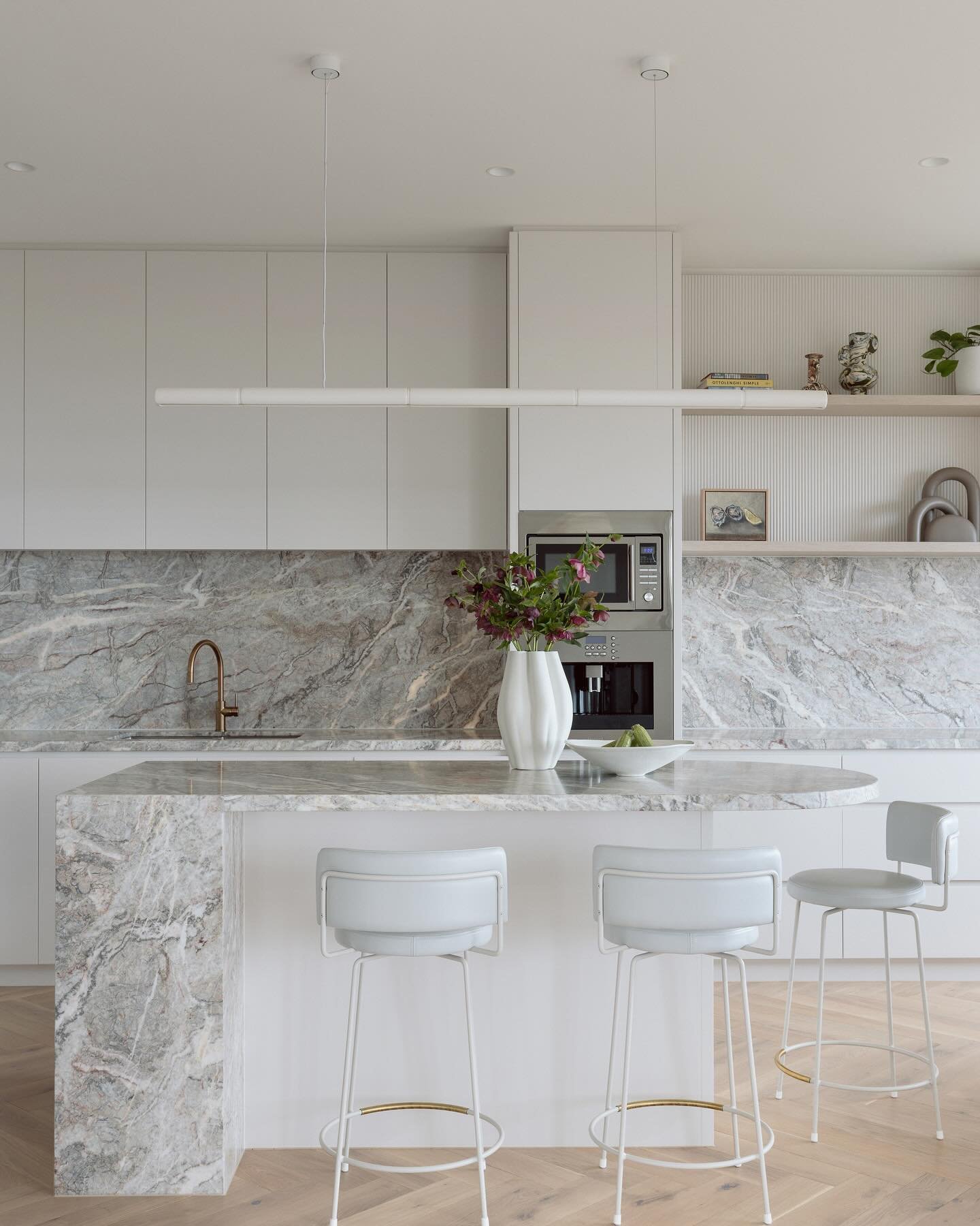 Extending the kitchen beyond the central column housing the microwave and coffee machine created a more harmonious and unified space, providing a beautiful, functional backdrop.

The striking Fior di Pesco marble on the benchtops, splashback, island 